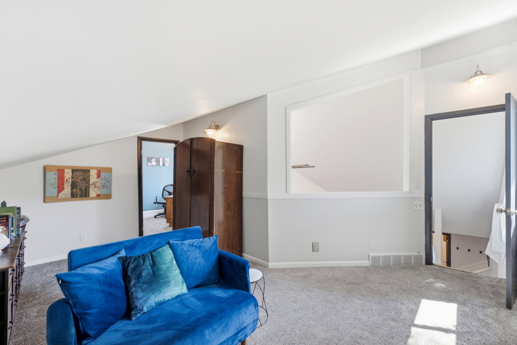 Carpeted loft area featuring a sloped ceiling, built-in wall niche, and an open doorway