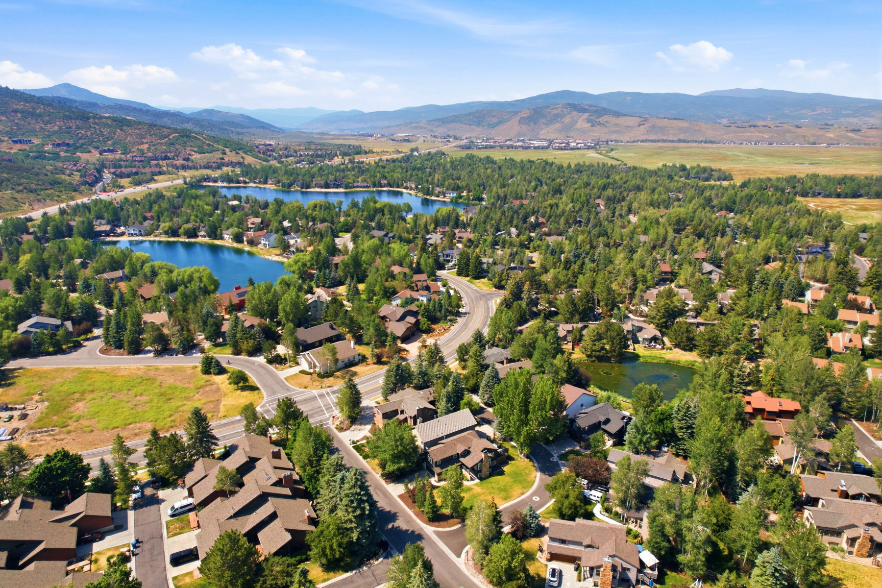 Expansive residential area featuring two lakes, dense tree coverage, and paved roadways