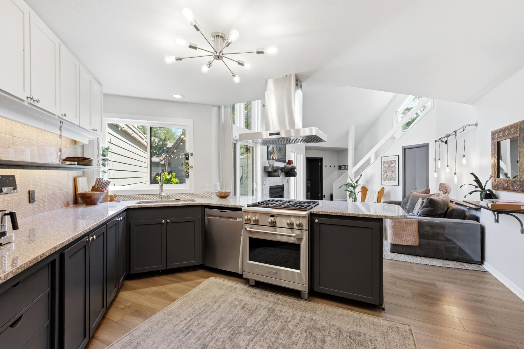 Modern kitchen featuring stainless steel appliances, granite countertops, two-tone cabinetry, wood-finish flooring, and a contemporary ceiling light fixture