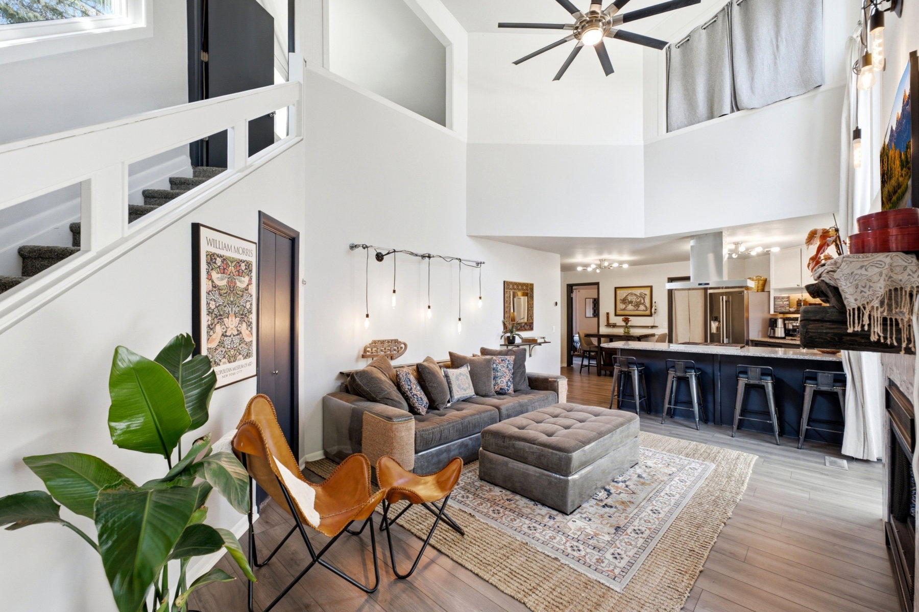 Open-concept living space featuring high ceilings, wood-finish flooring, a contemporary ceiling fan, and a kitchen island with seating