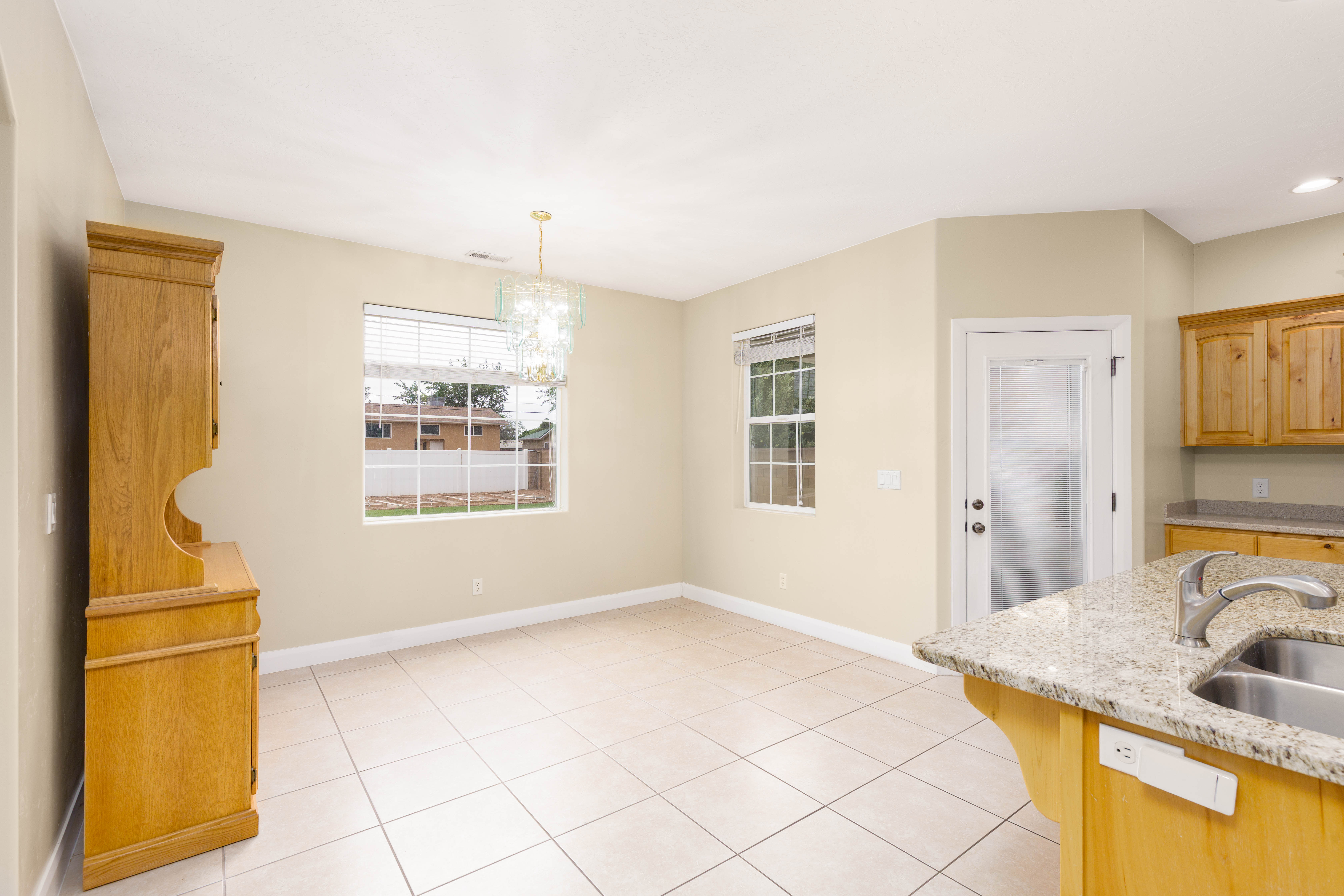 Kitchen space featuring an island with a double basin sink, light-toned cabinetry, and granite countertops