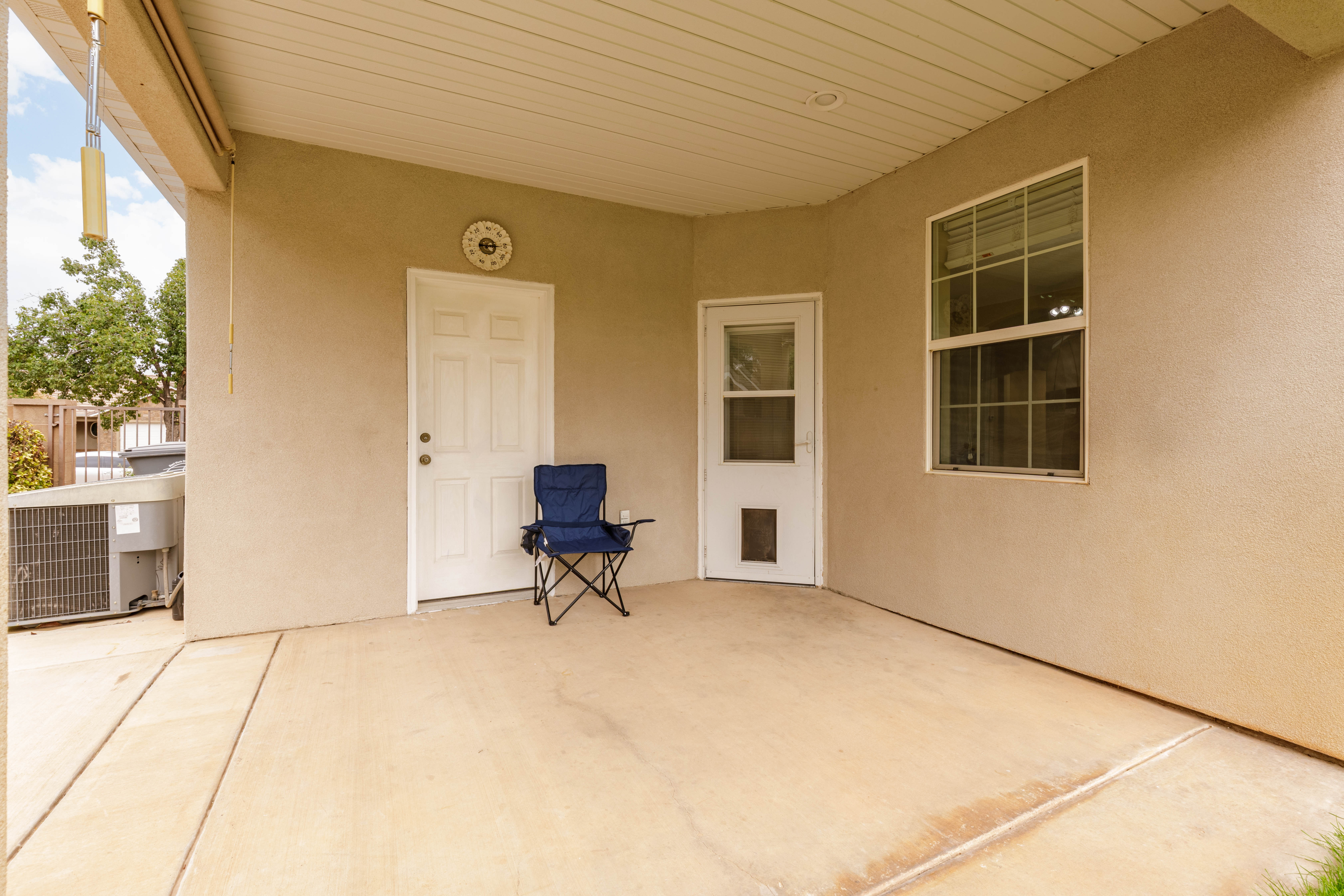 Covered patio space featuring a stucco exterior, concrete flooring, and a white paneled door