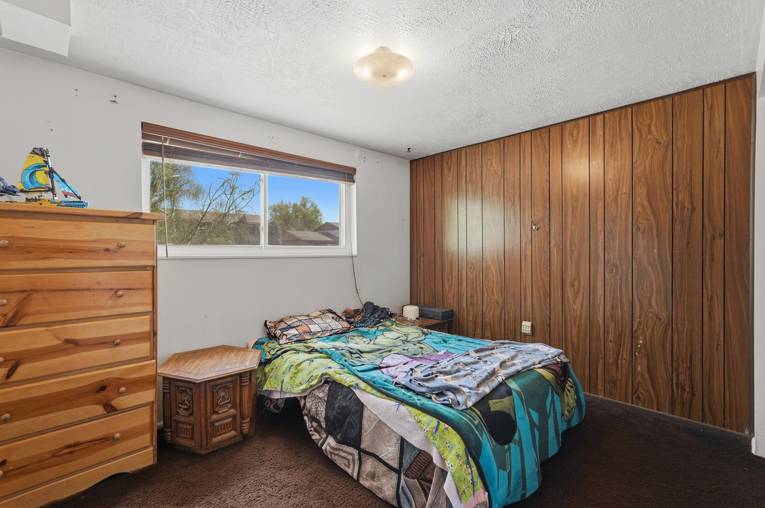 Room featuring a wood-panel accent wall and a window with blinds