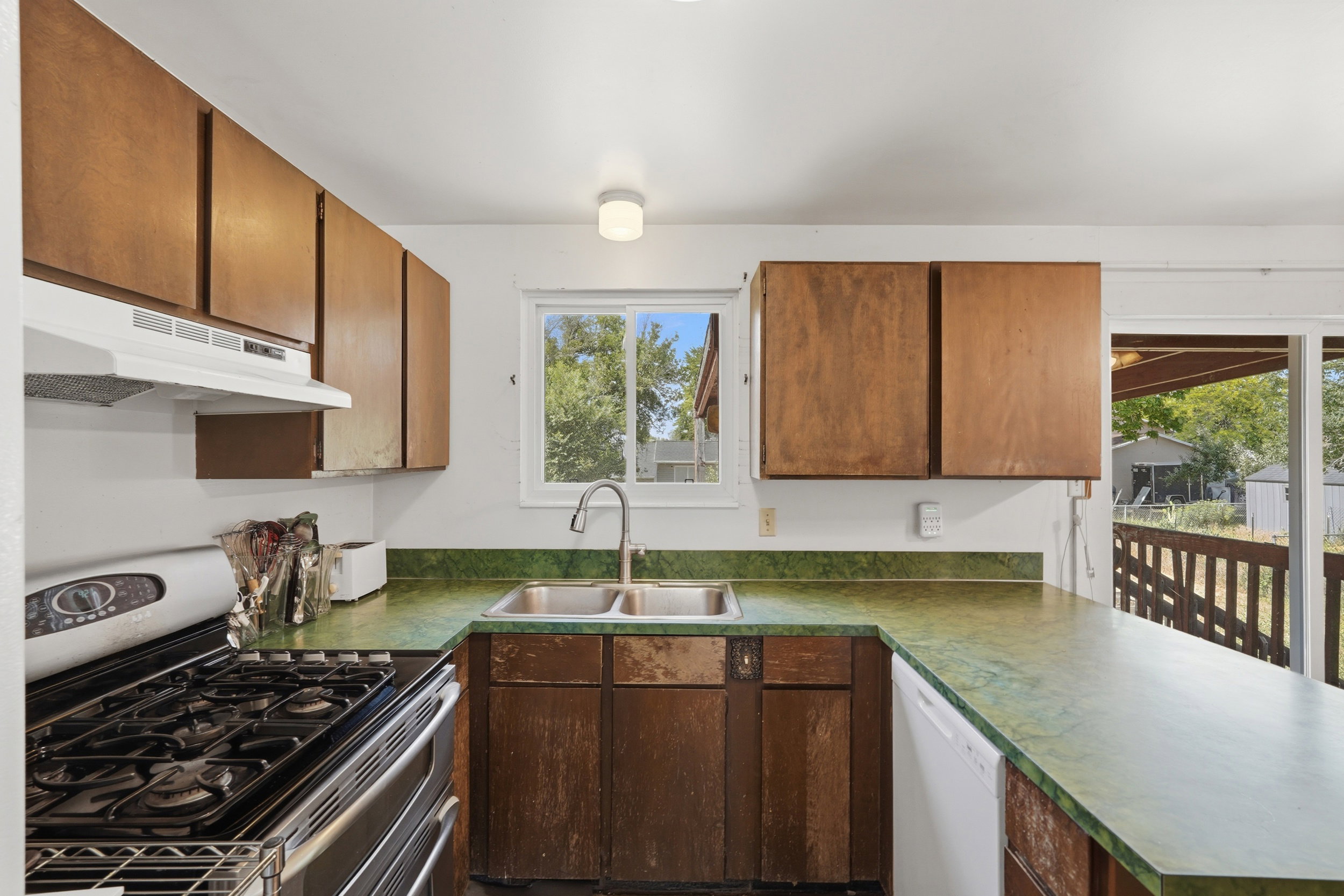 Kitchen featuring wood-finish cabinetry, a double basin sink with a gooseneck faucet, and a gas range
