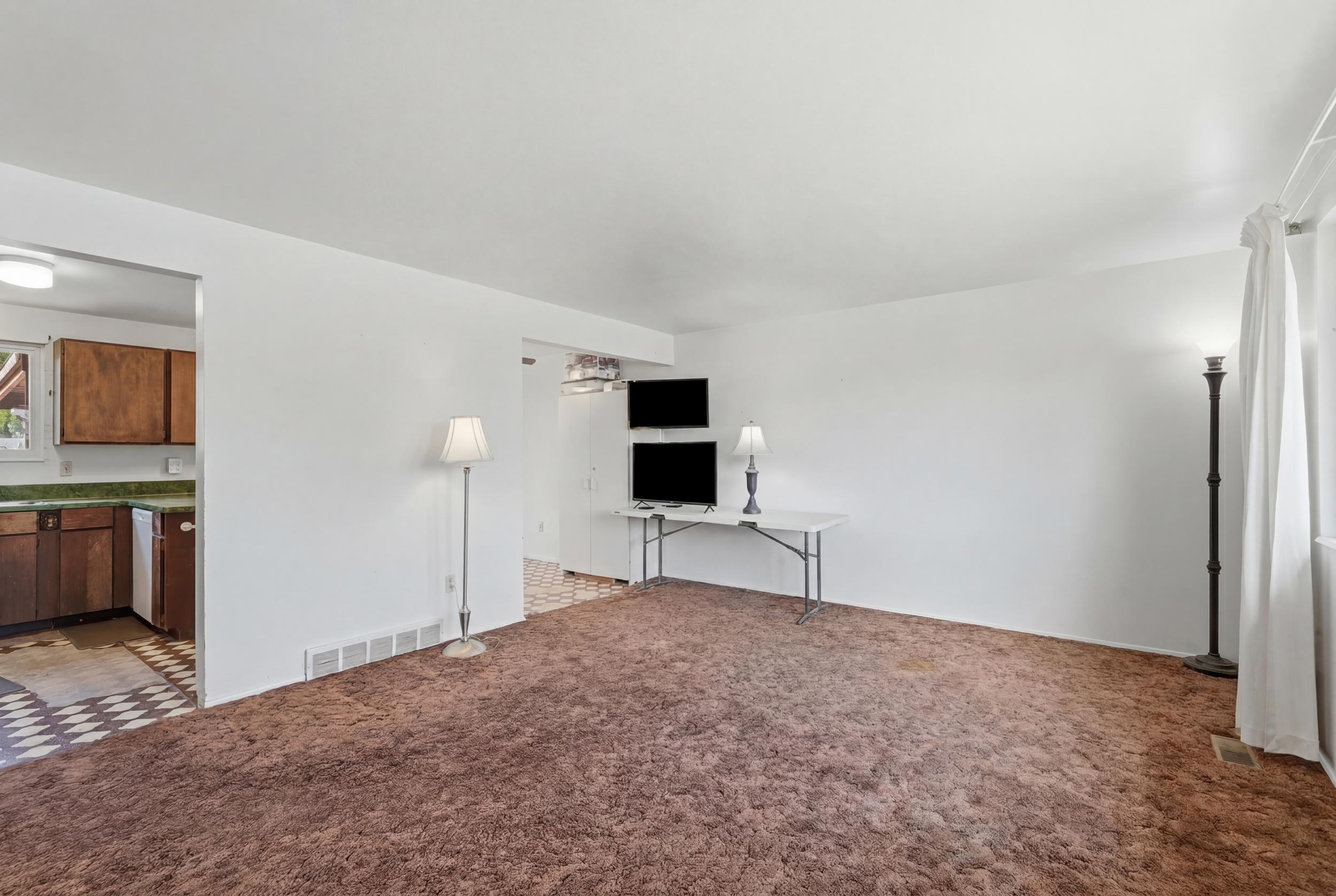 Spacious common area with brown carpet flooring and white walls