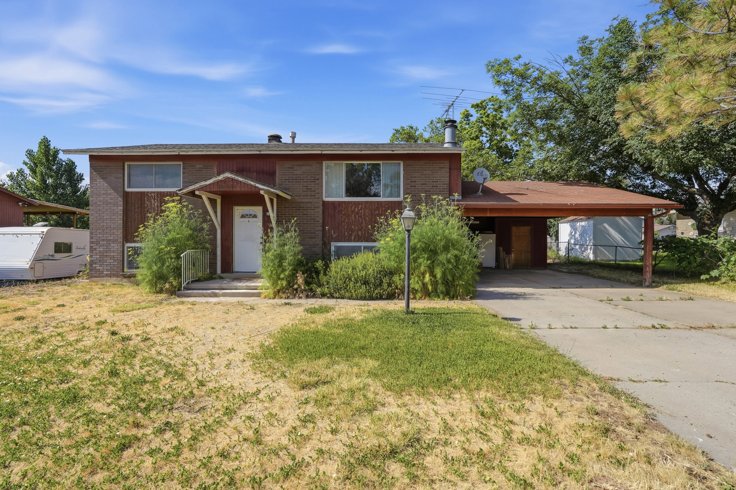 Two-story residence featuring brick and vertical siding facade, an attached carport, and a covered entryway