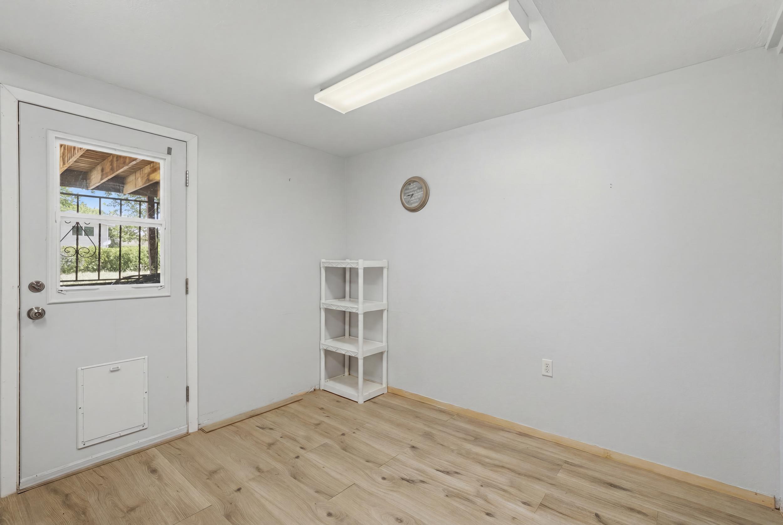 Entryway featuring a light gray door with an integrated window, wood-finish flooring, and white walls