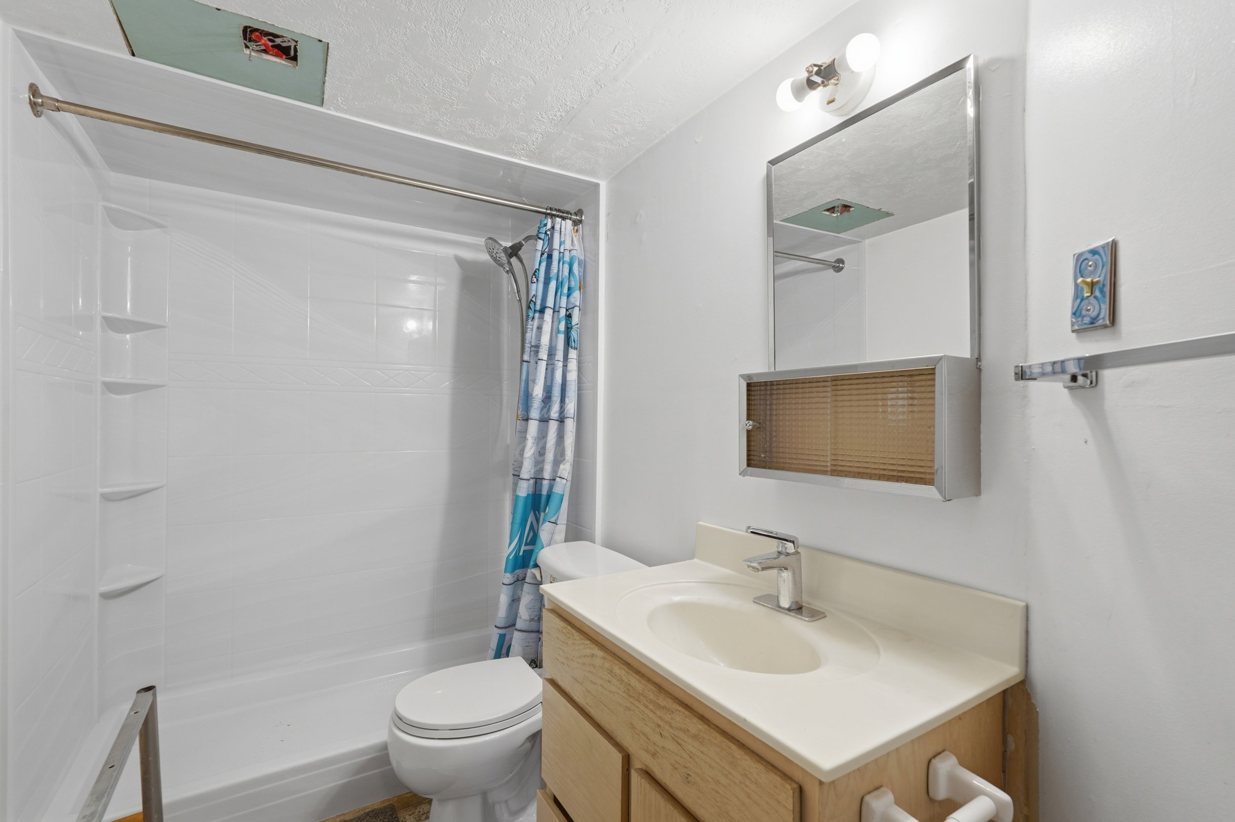 Full bathroom featuring a white shower-over-tub unit, a toilet, and a vanity with an integrated sink
