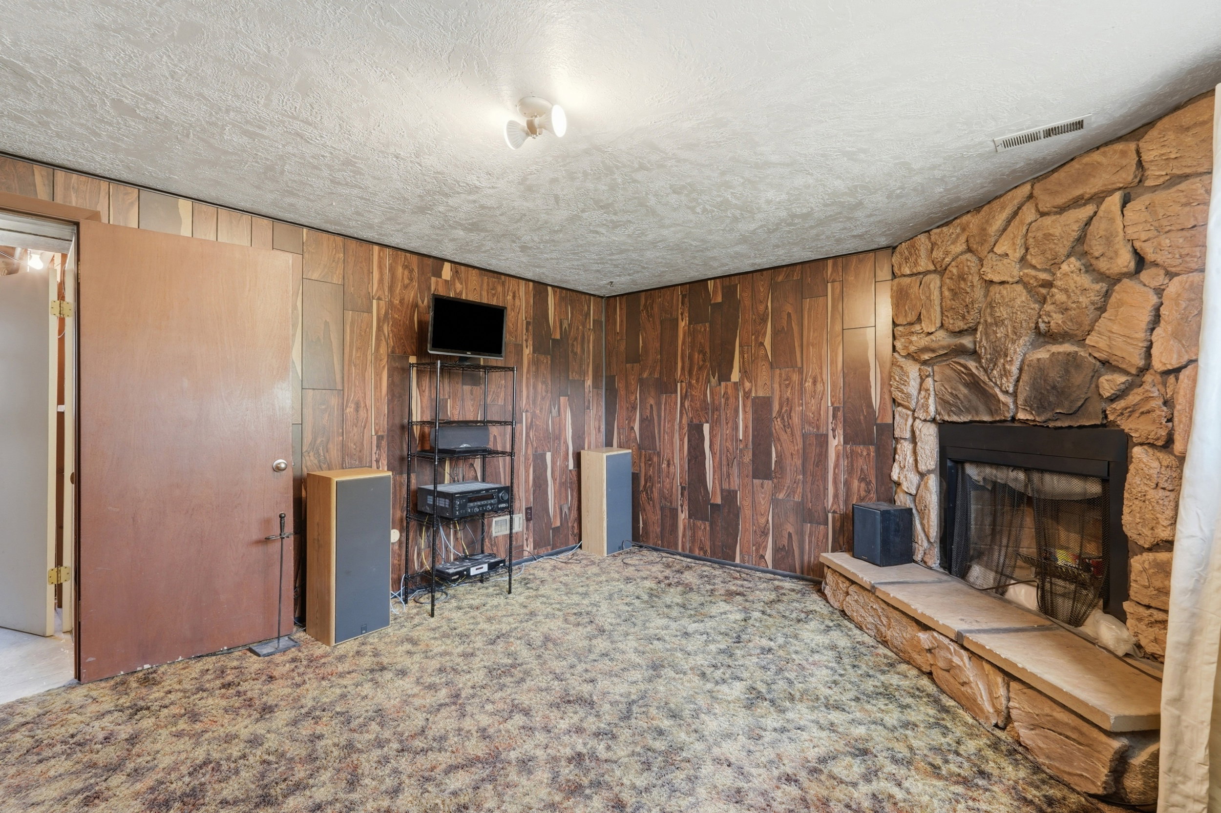Focal stone-clad fireplace with hearth and metal grate