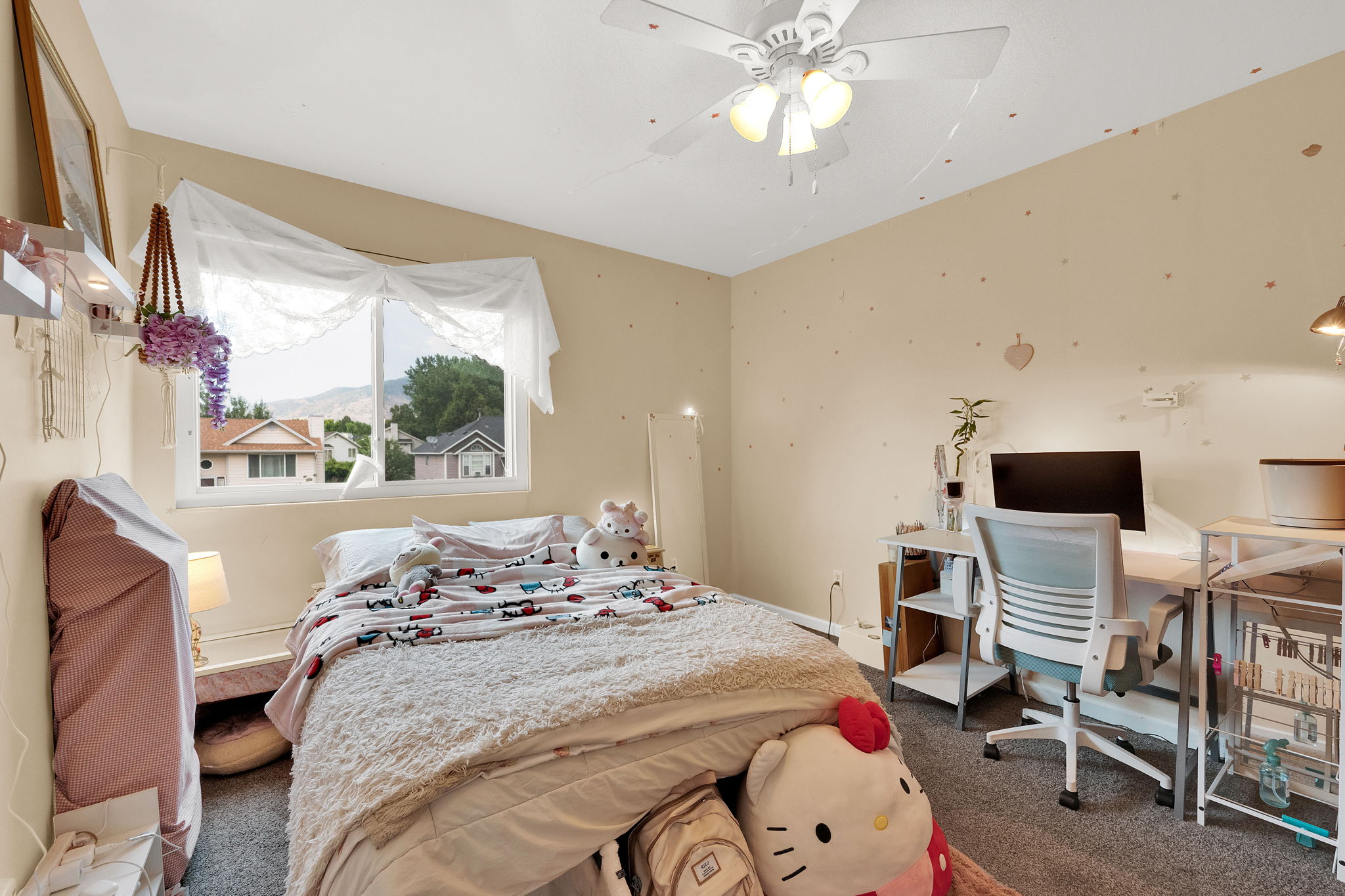 Carpeted room featuring a ceiling fan, a window with a mountain backdrop, and neutral-toned walls