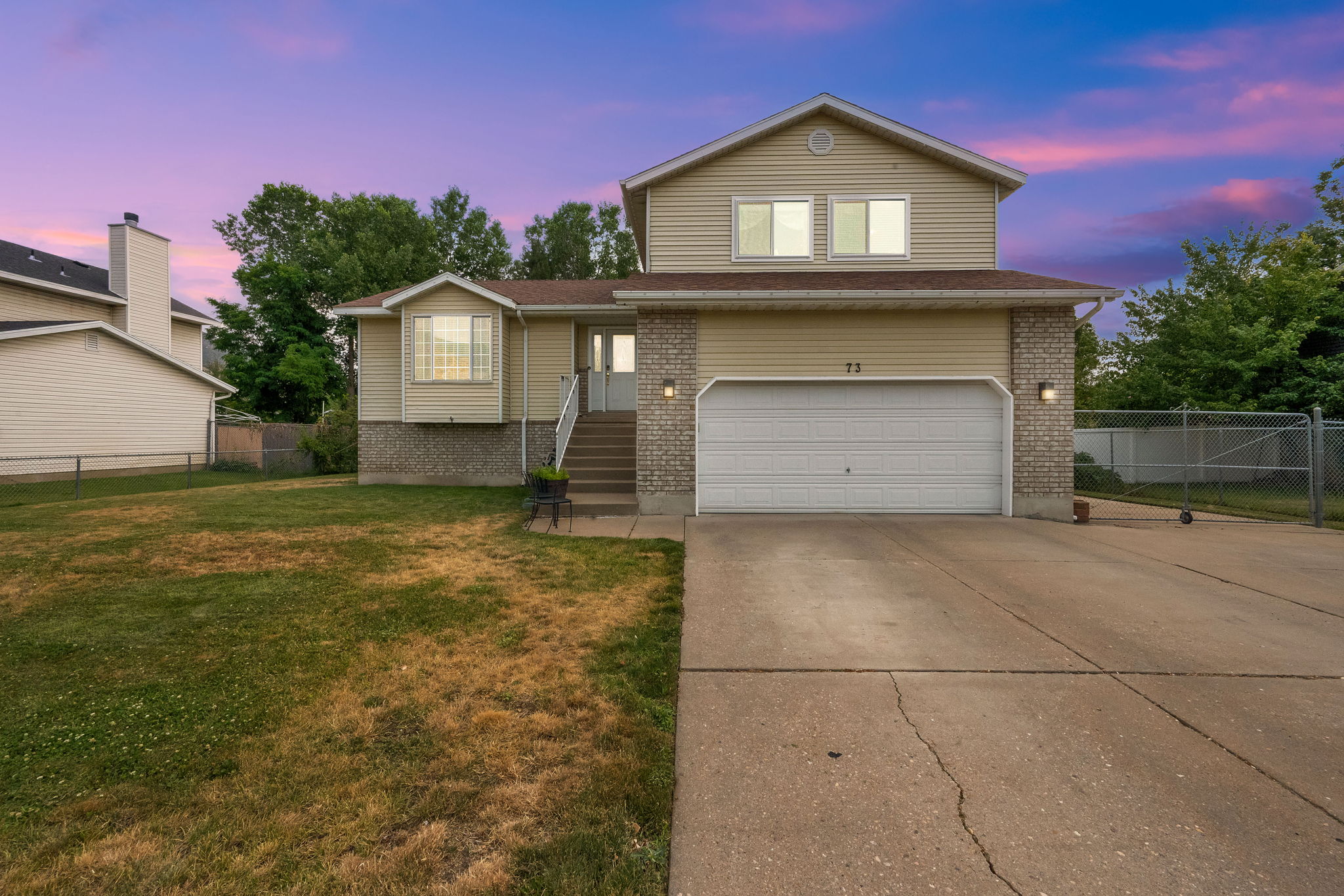 Split-level residence featuring a two-car garage, concrete driveway, and a front bay window