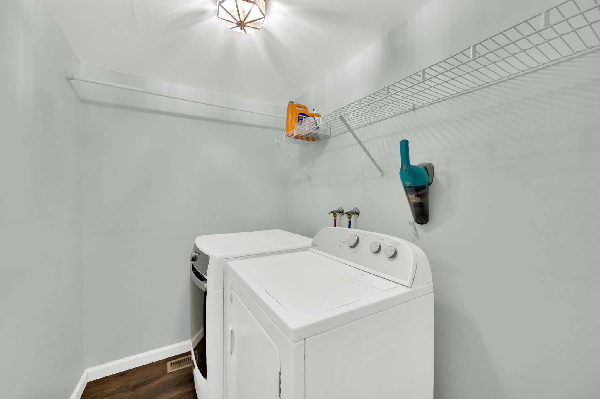 Dedicated laundry area featuring a light blue wall color and wood-finish flooring