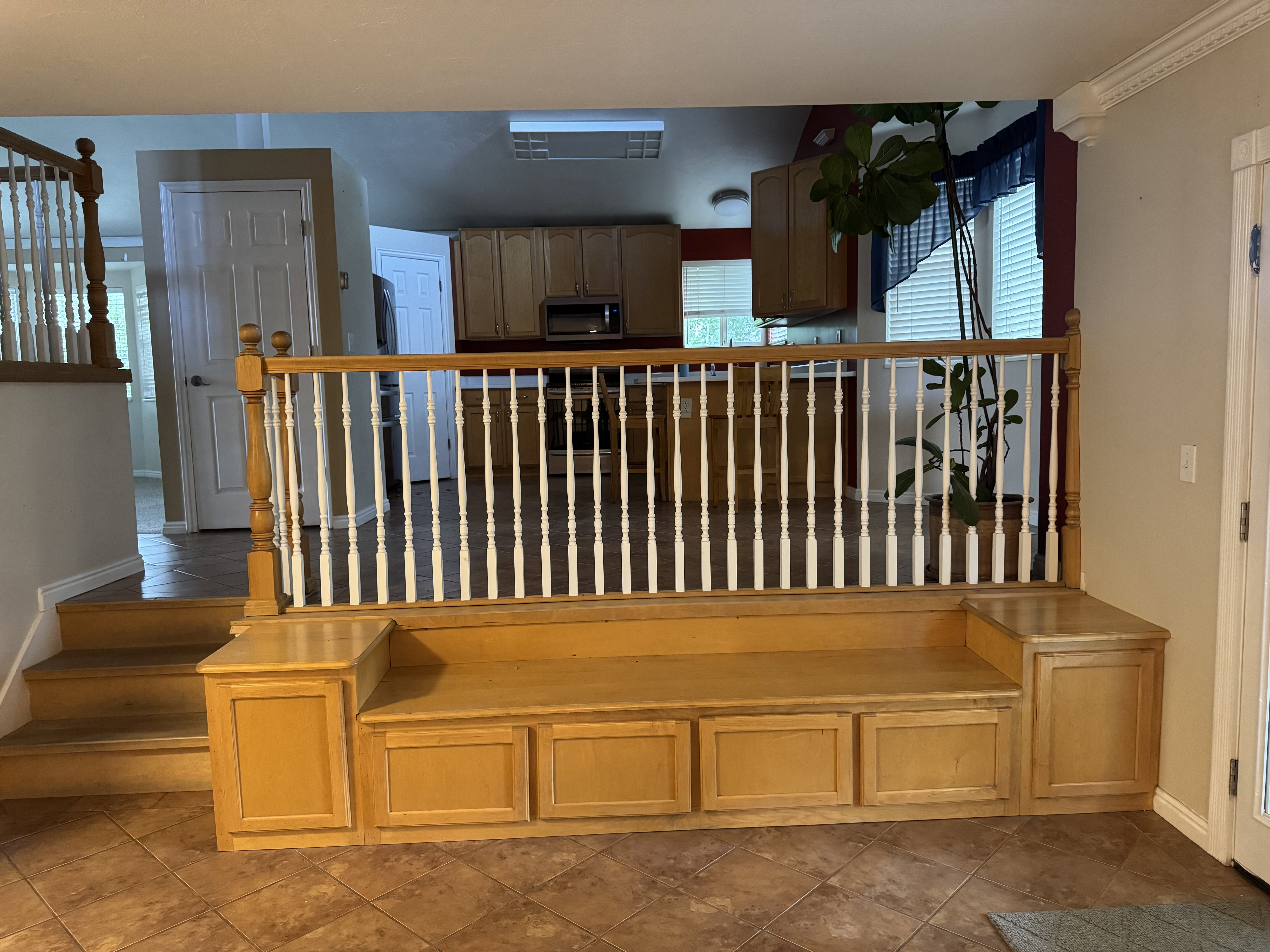 Built-in wood-finish bench seating with integrated storage, featuring a light wood railing and white balusters
