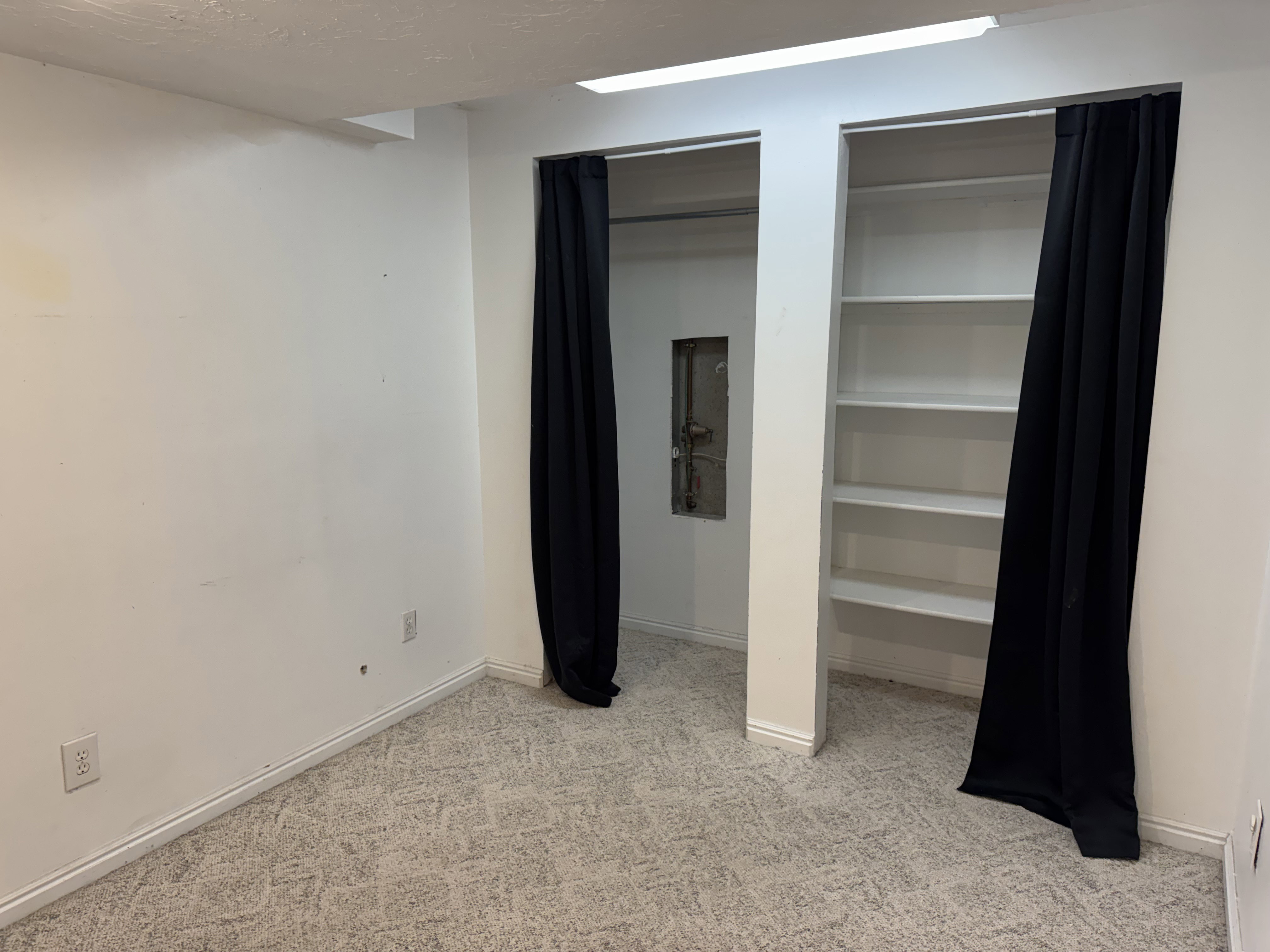 Carpeted room featuring white walls, built-in shelving, and baseboard molding