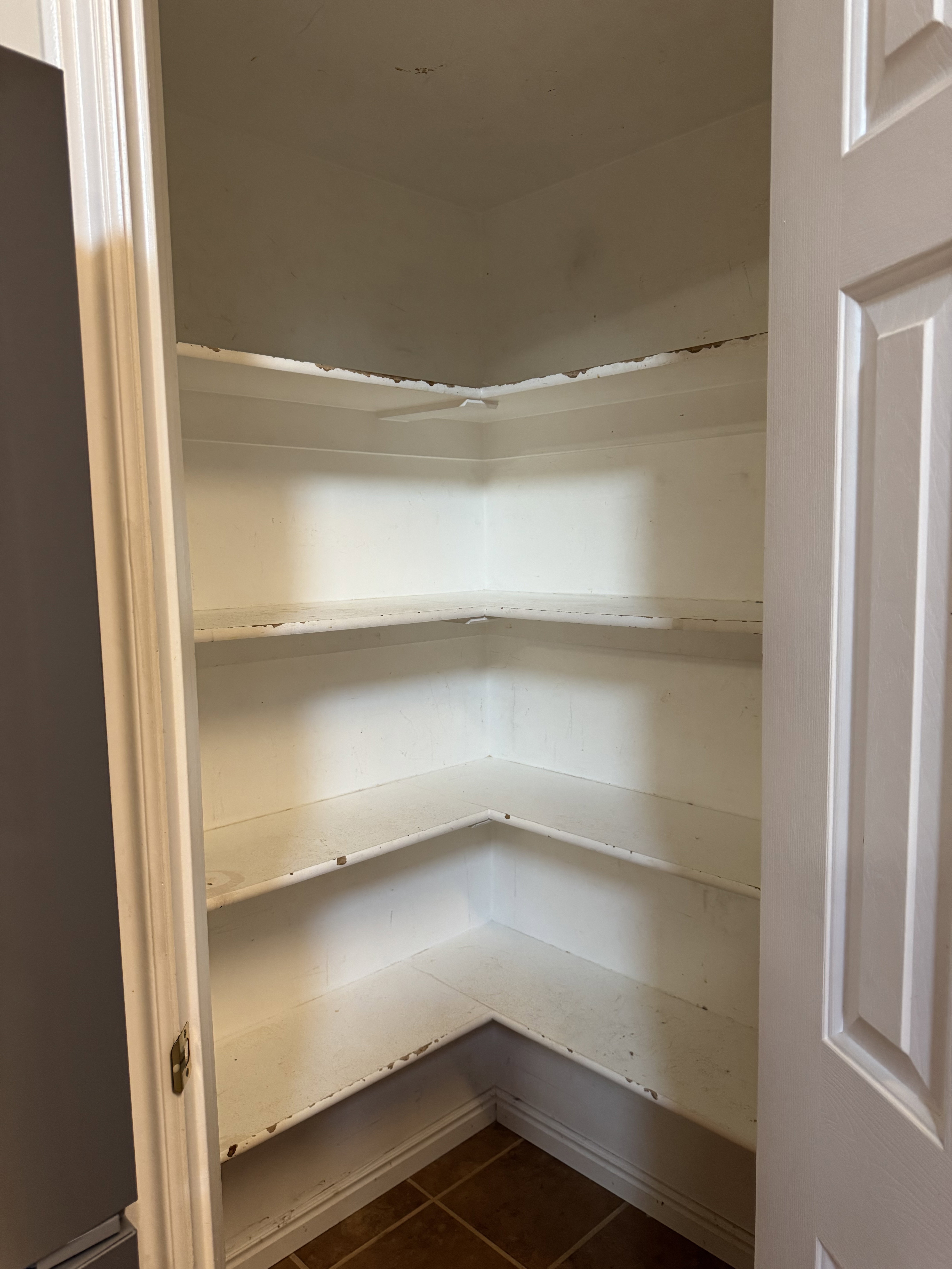 Built-in corner pantry featuring five levels of shelving and tile flooring