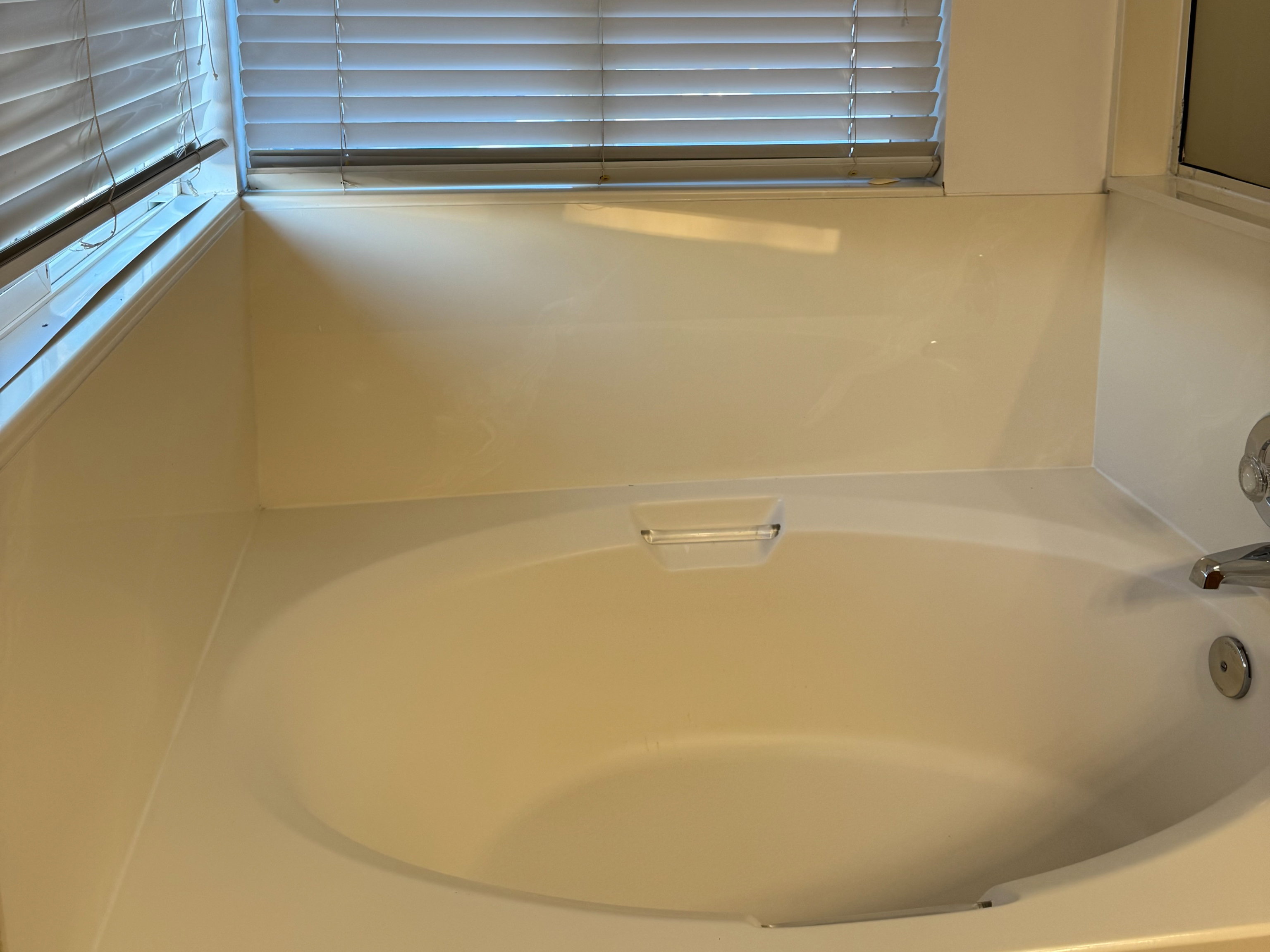 Built-in soaking tub with a window featuring horizontal blinds