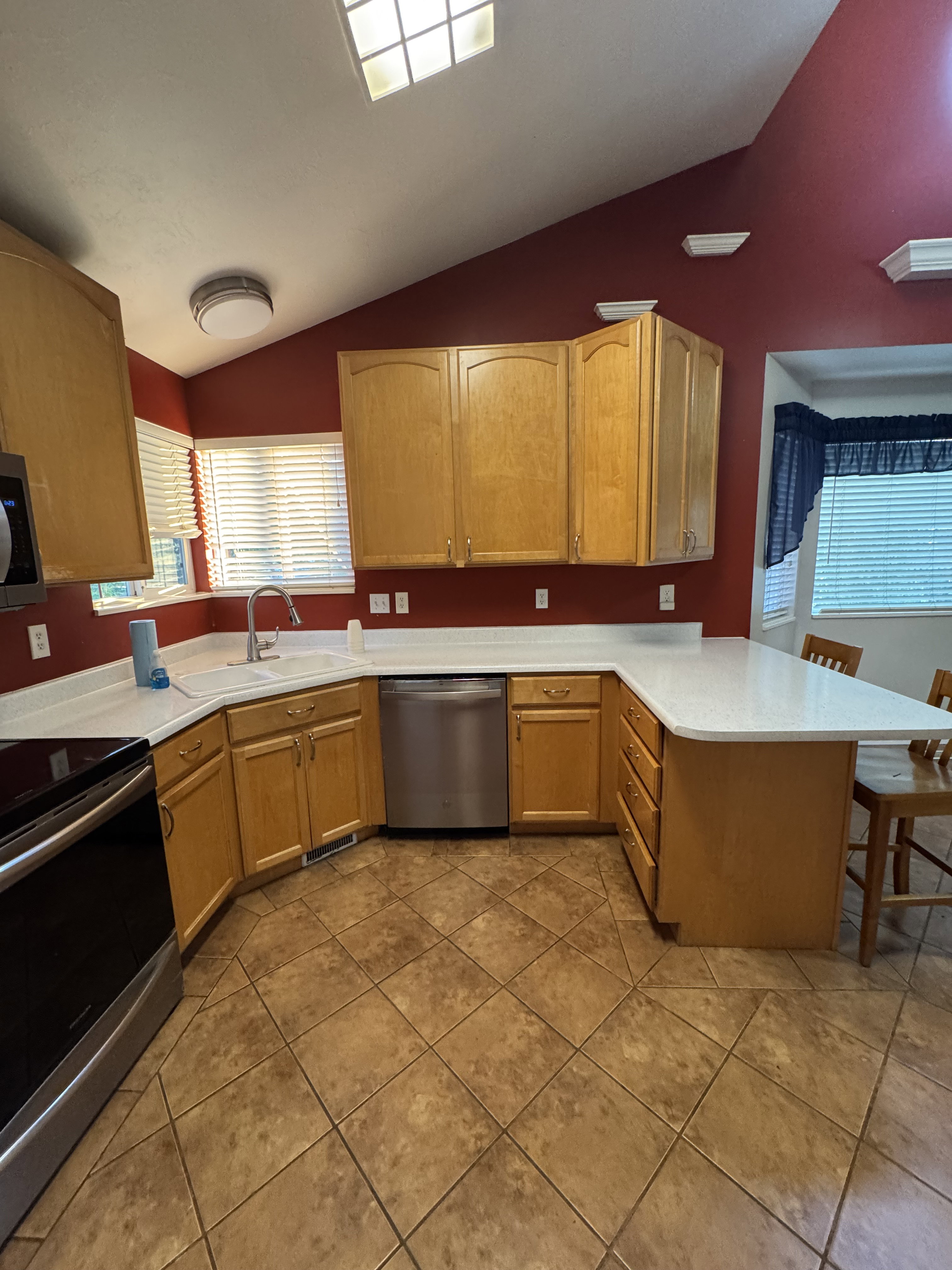 Kitchen featuring wood cabinetry, white countertops, stainless steel appliances, and diagonal tile flooring