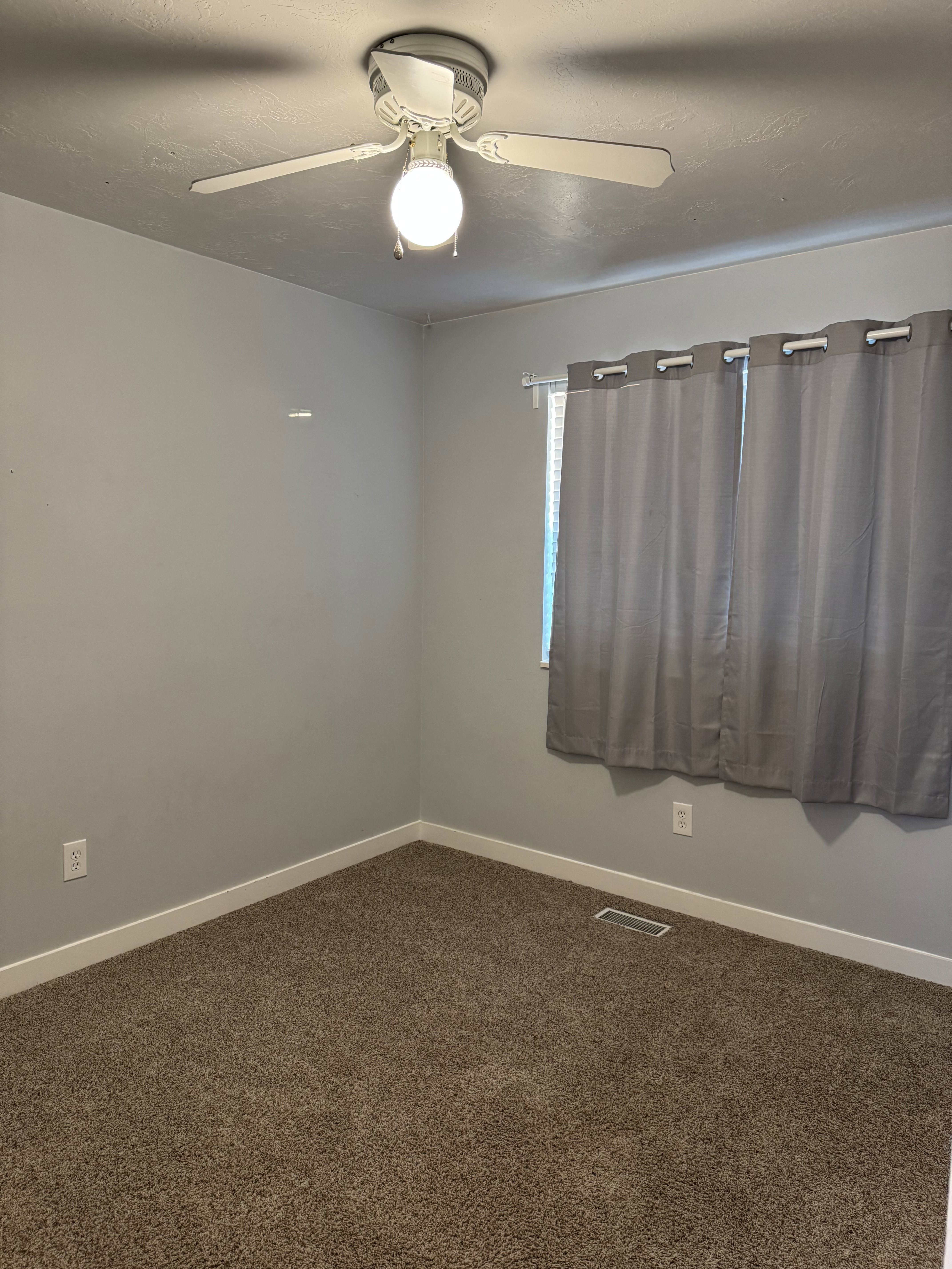 Neutral tone wall paint, textured ceiling, ceiling fan with integrated lighting, window with window treatment, and carpet flooring