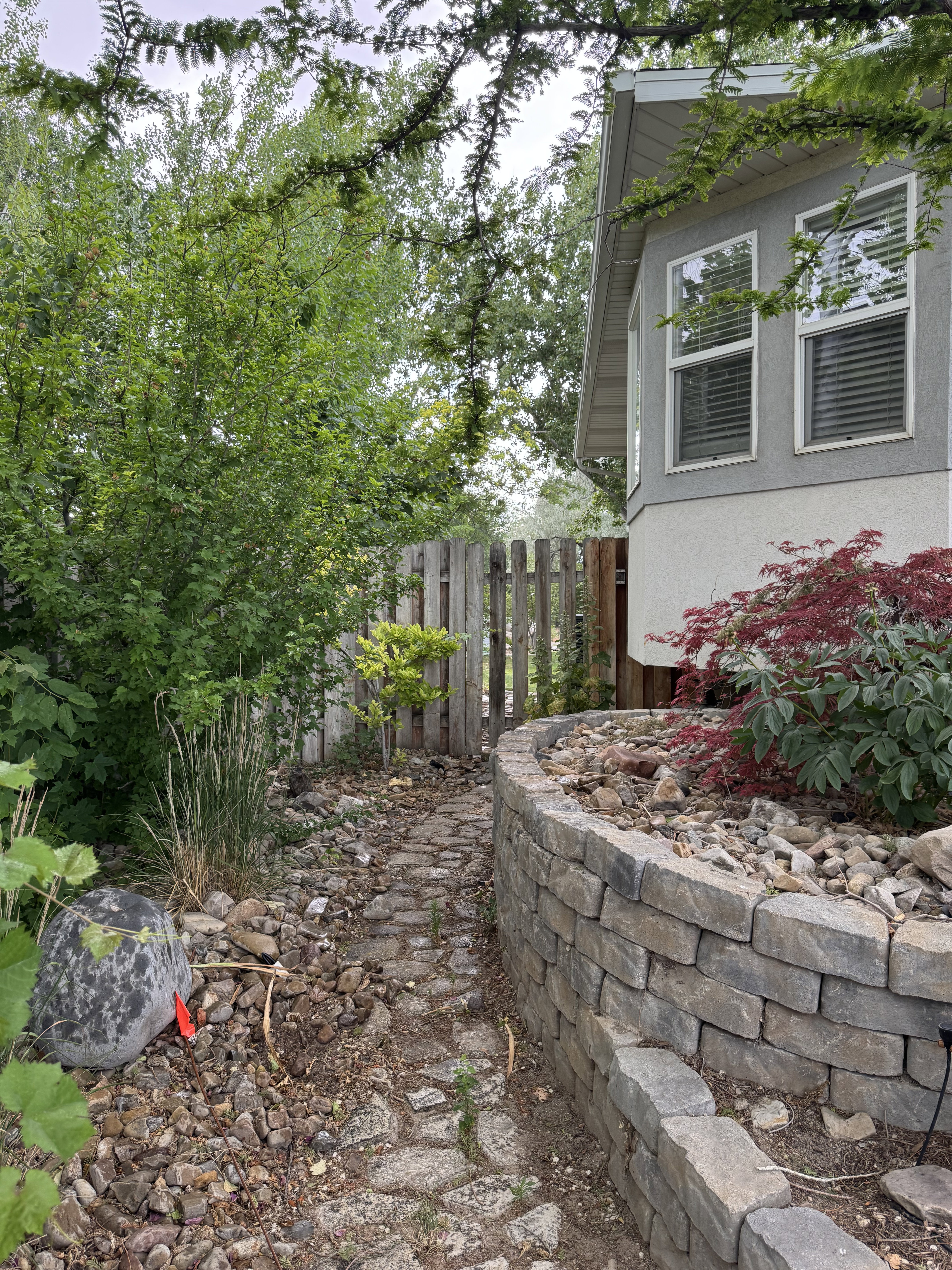 Stone paver pathway bordered by a curved retaining wall