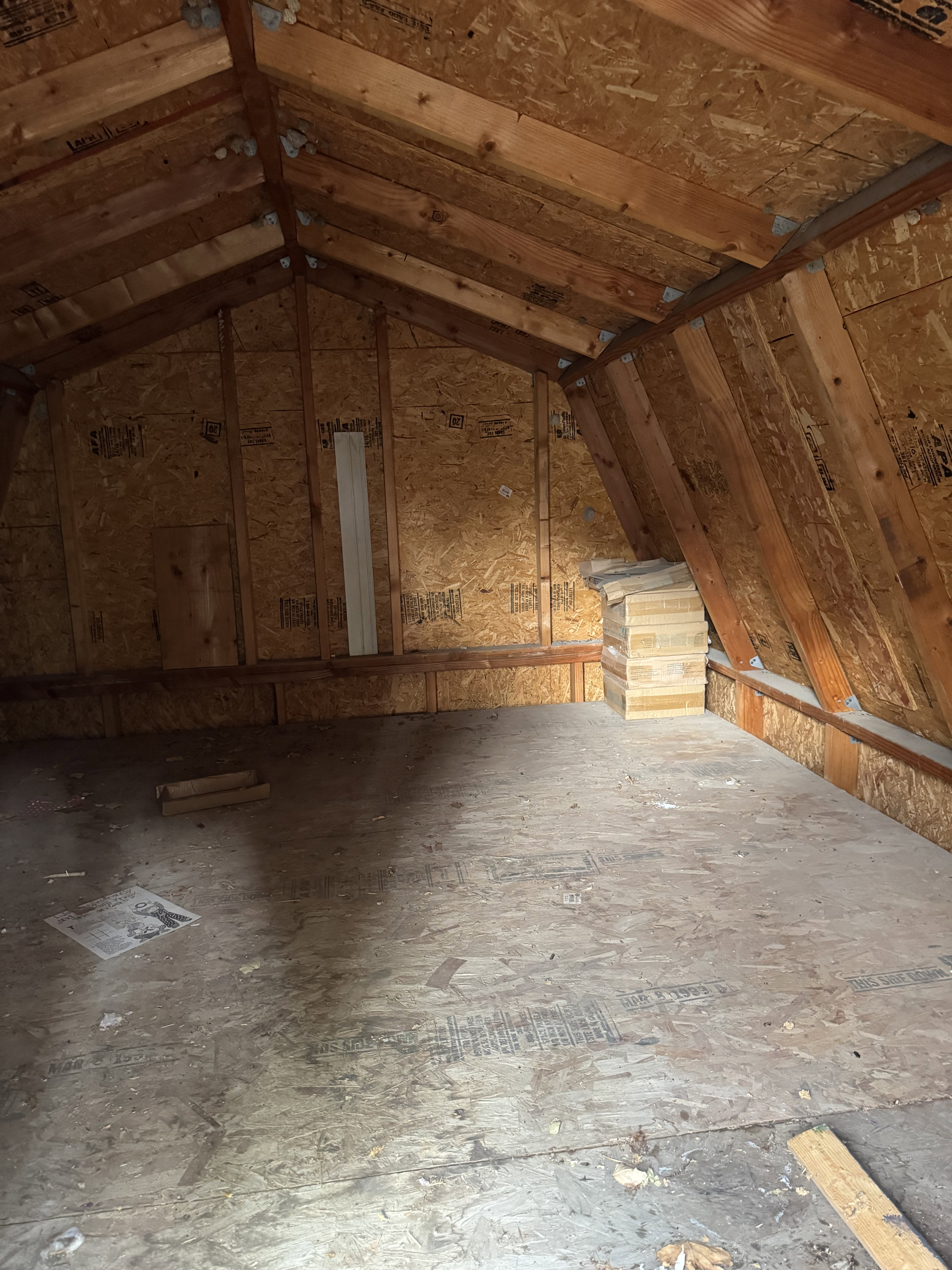Shed has a spacious attic space featuring exposed wood beams and oriented strand board construction