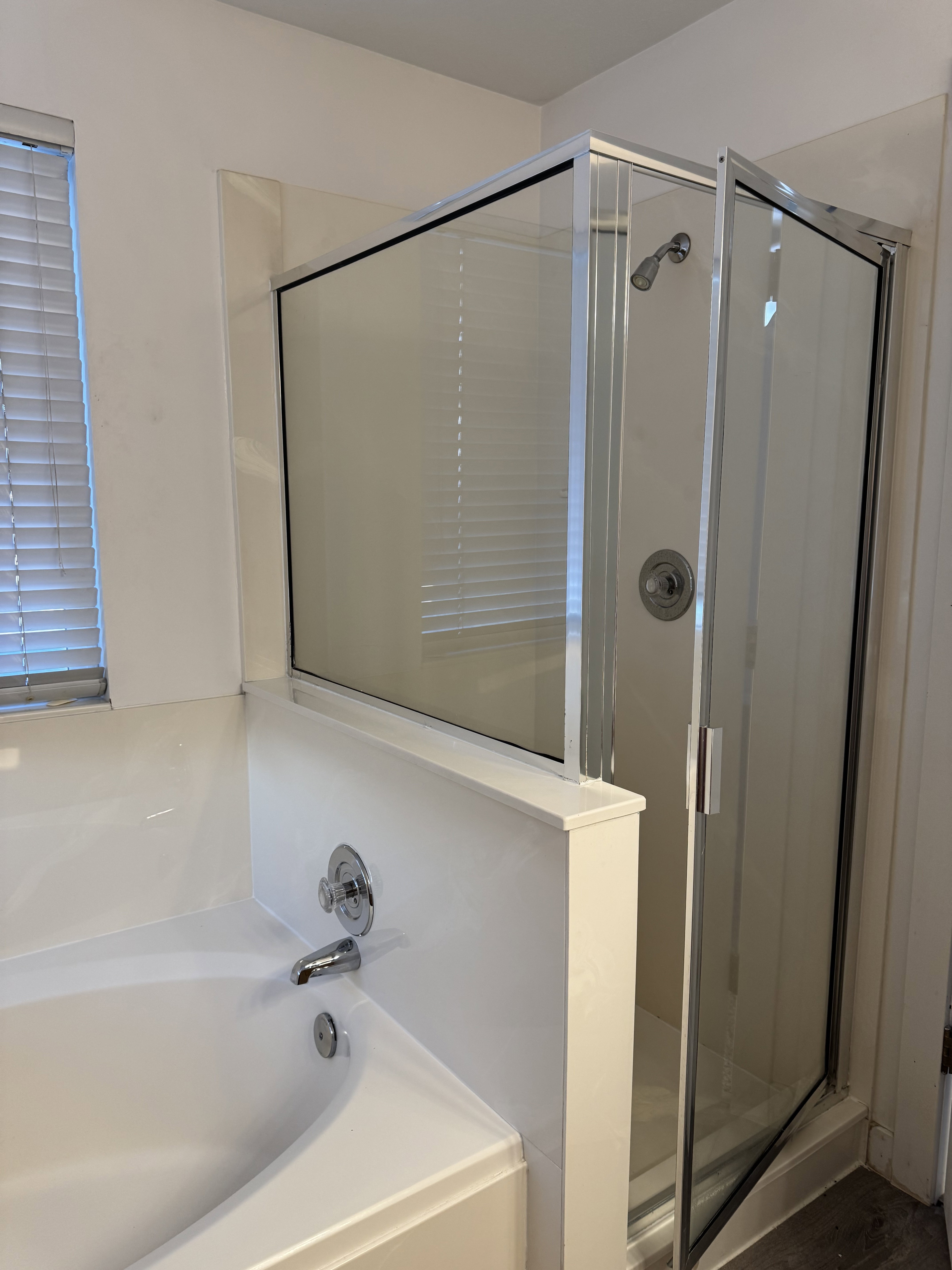 Alcove bathtub with chrome fixtures and an adjacent glass-enclosed shower with a chrome showerhead
