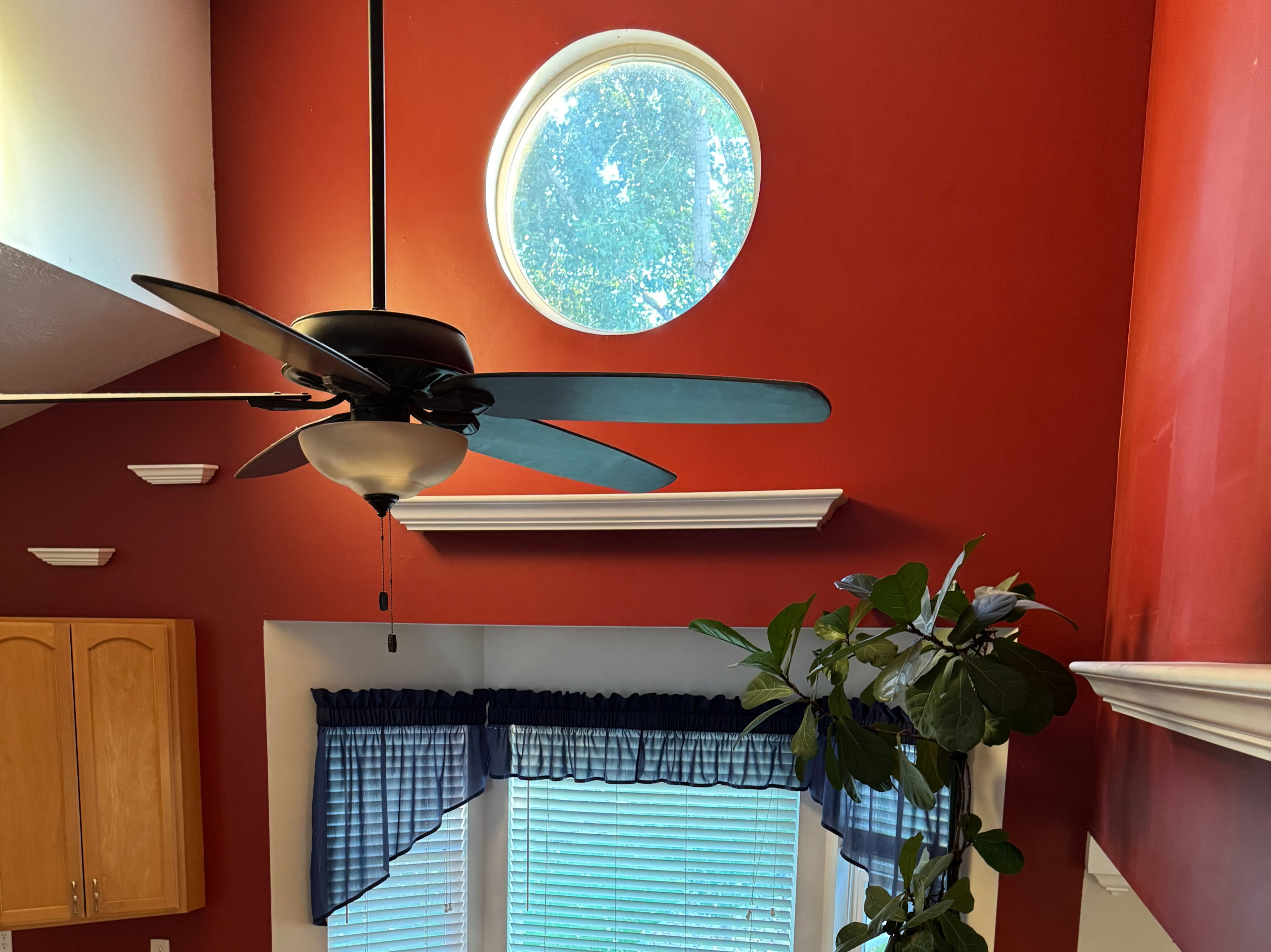 Two-story ceiling with a circular architectural window and contemporary ceiling fan