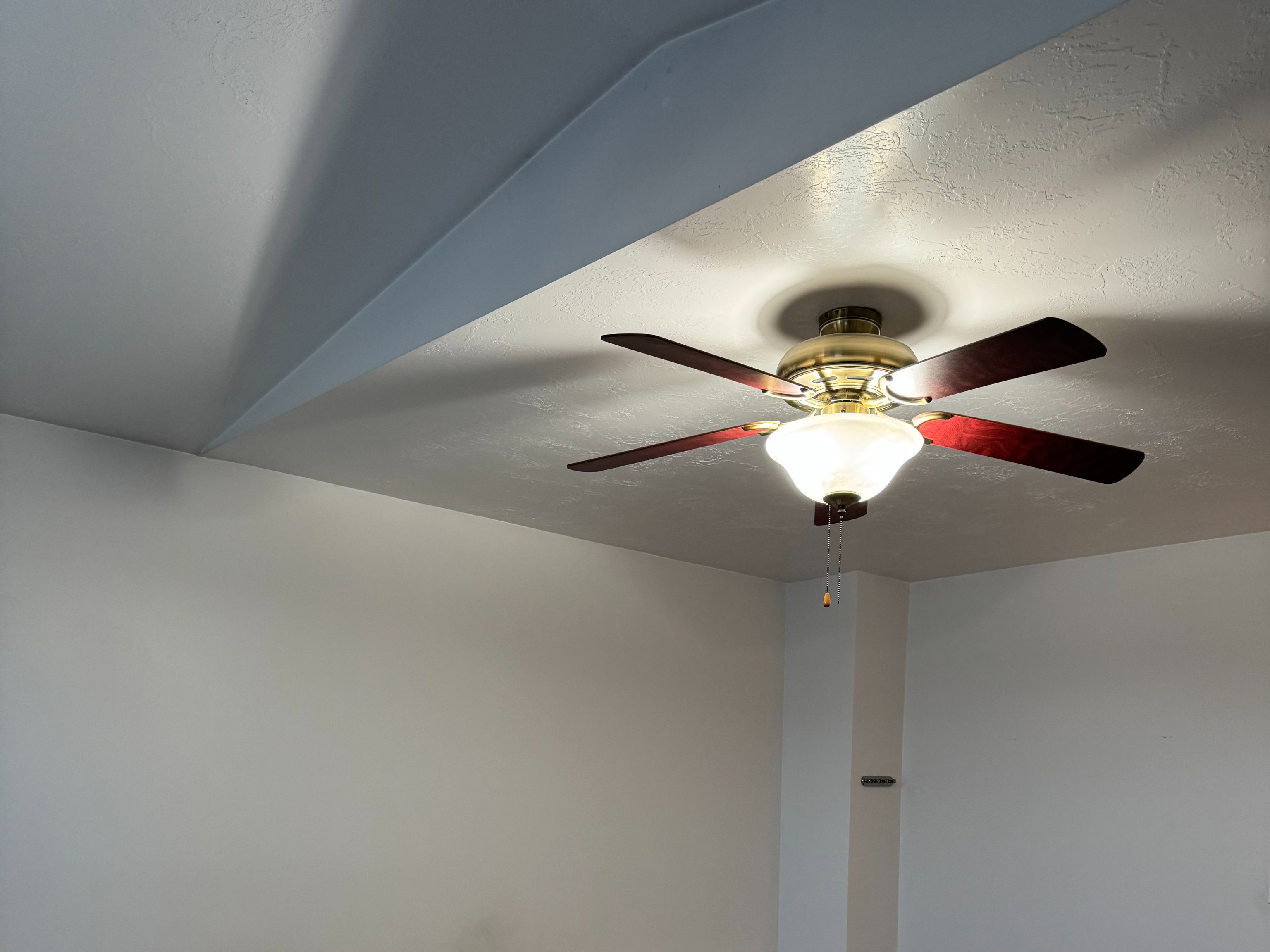 Recessed ceiling fan with integrated lighting, textured carpeting, and white baseboards