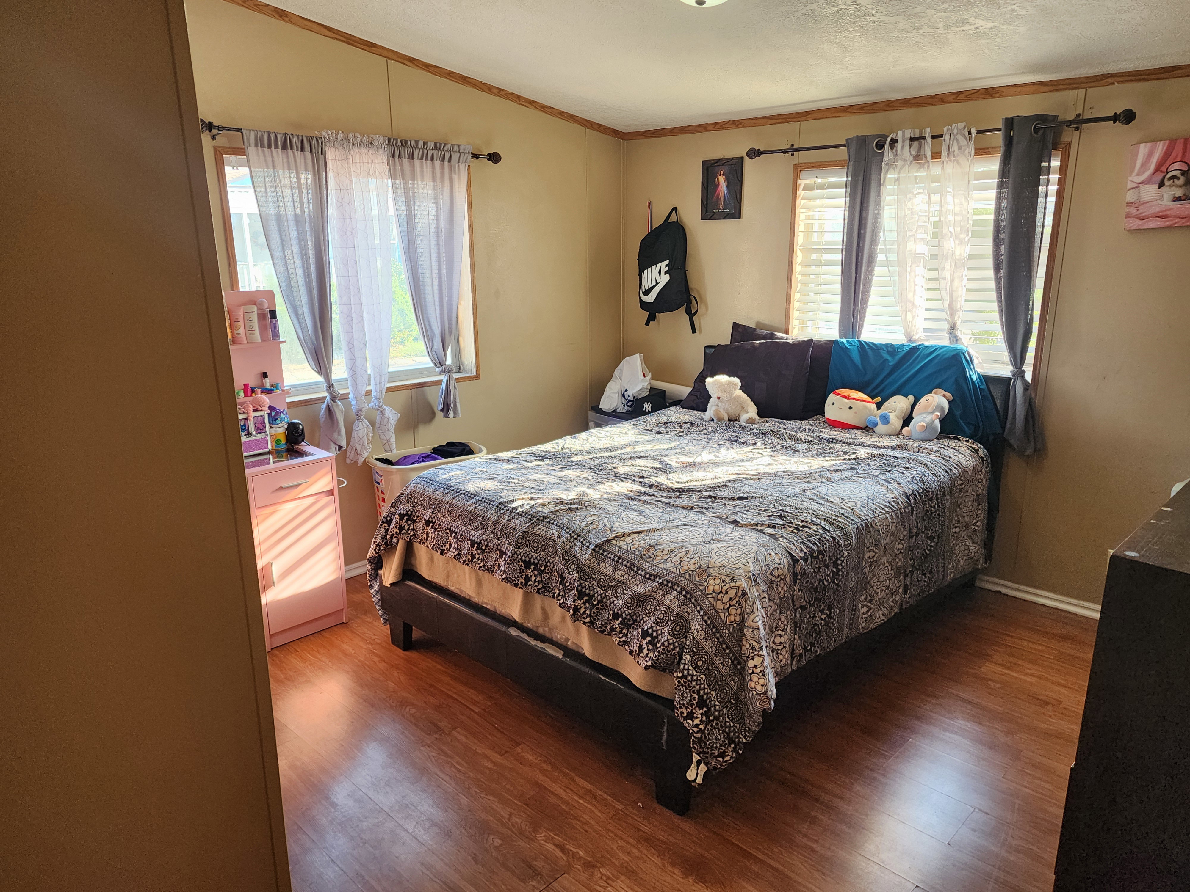 Room featuring wood-finish flooring, two windows with horizontal blinds, and a ceiling-mounted light fixture