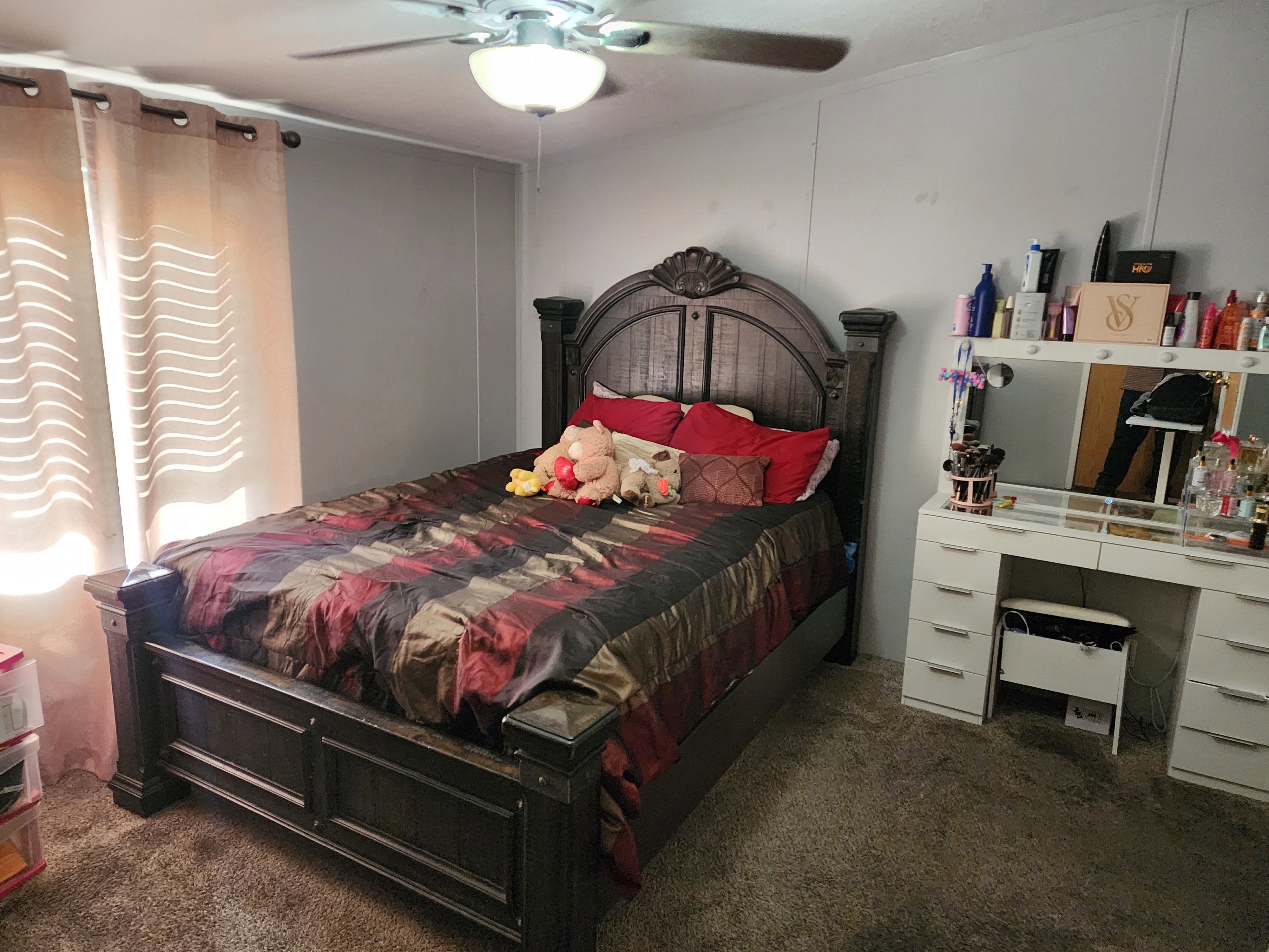 Bedroom featuring a ceiling fan with integrated lighting, wall-to-wall carpeting, and light-filtering window treatments