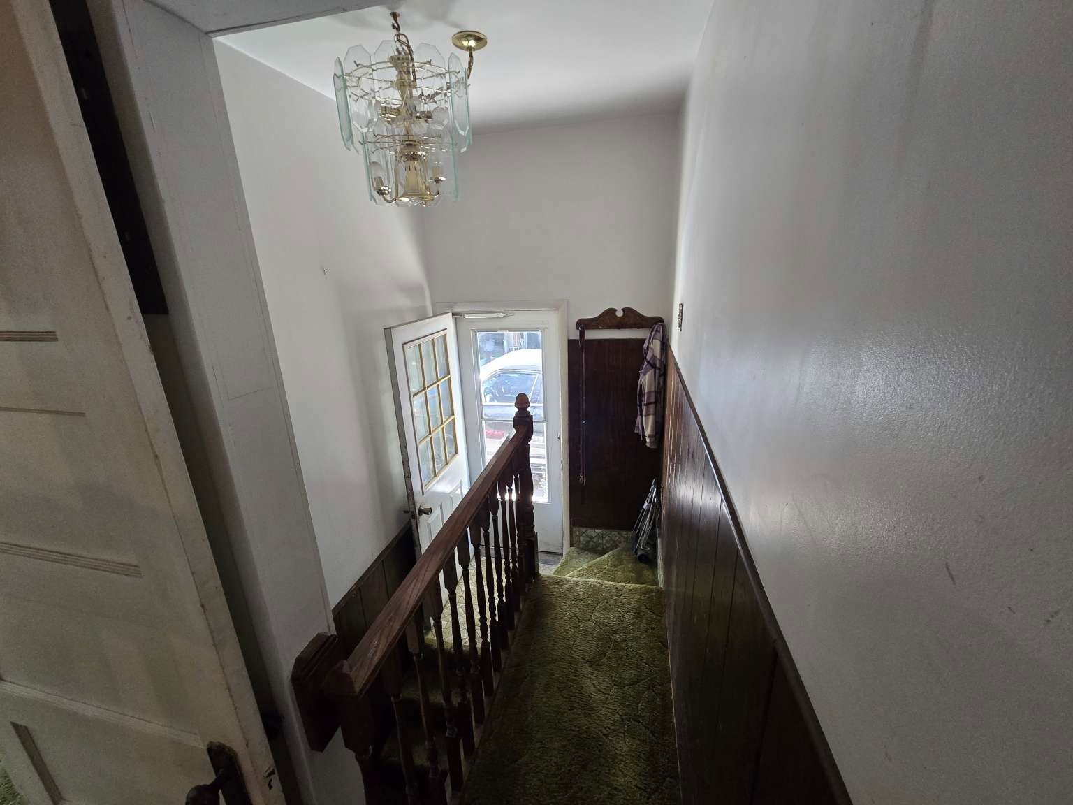 Stairwell featuring wood-finish paneling, an ornate chandelier, and a wood-finish banister