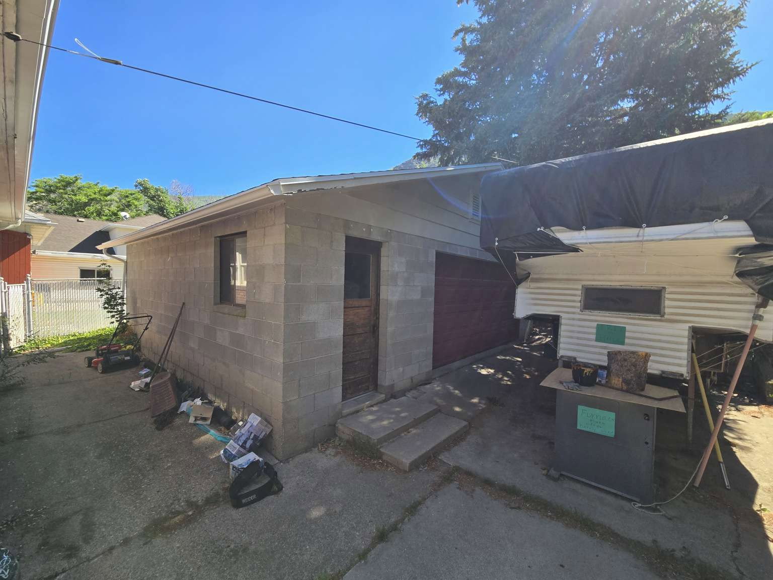 Detached utility building featuring concrete block construction, a single window, and a wooden entry door