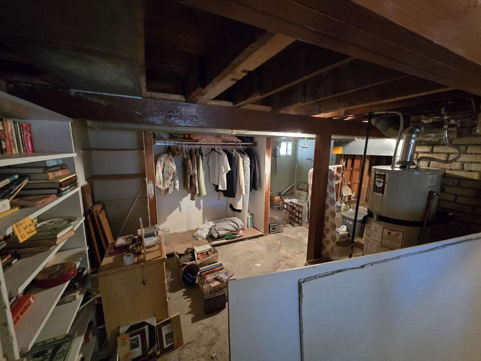 Unfinished basement offering exposed ceiling joists, concrete flooring, and a water heater