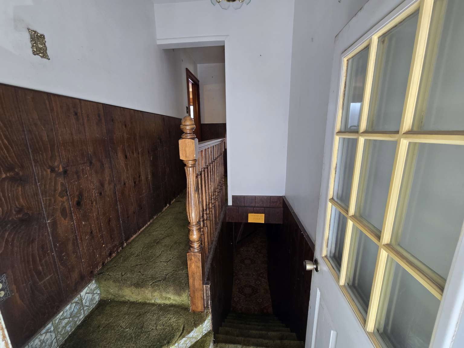 Stairwell featuring wood paneling, wood balusters, and a paneled door with glass inserts