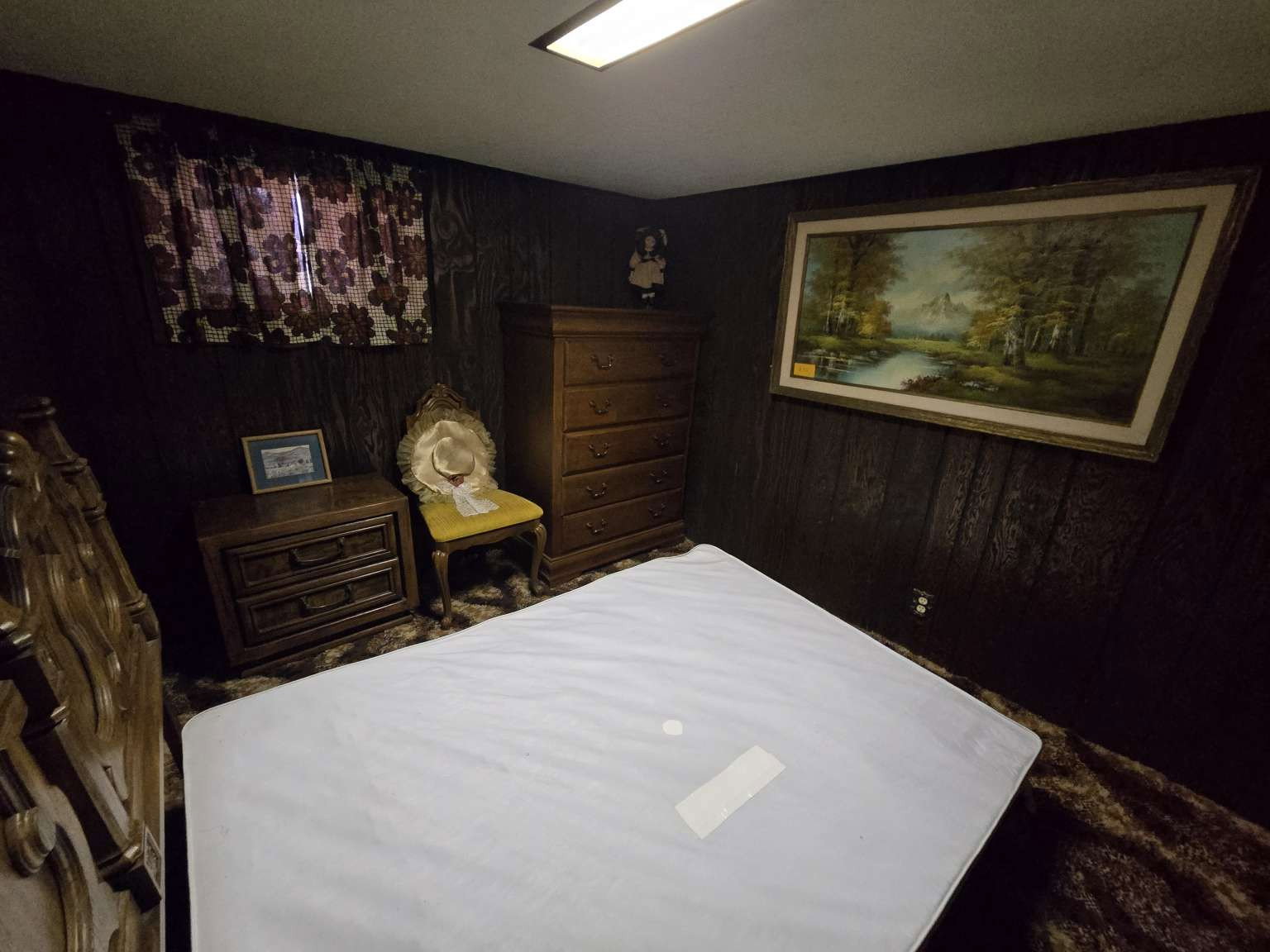 Room featuring dark wood-paneled walls and a window with patterned curtains