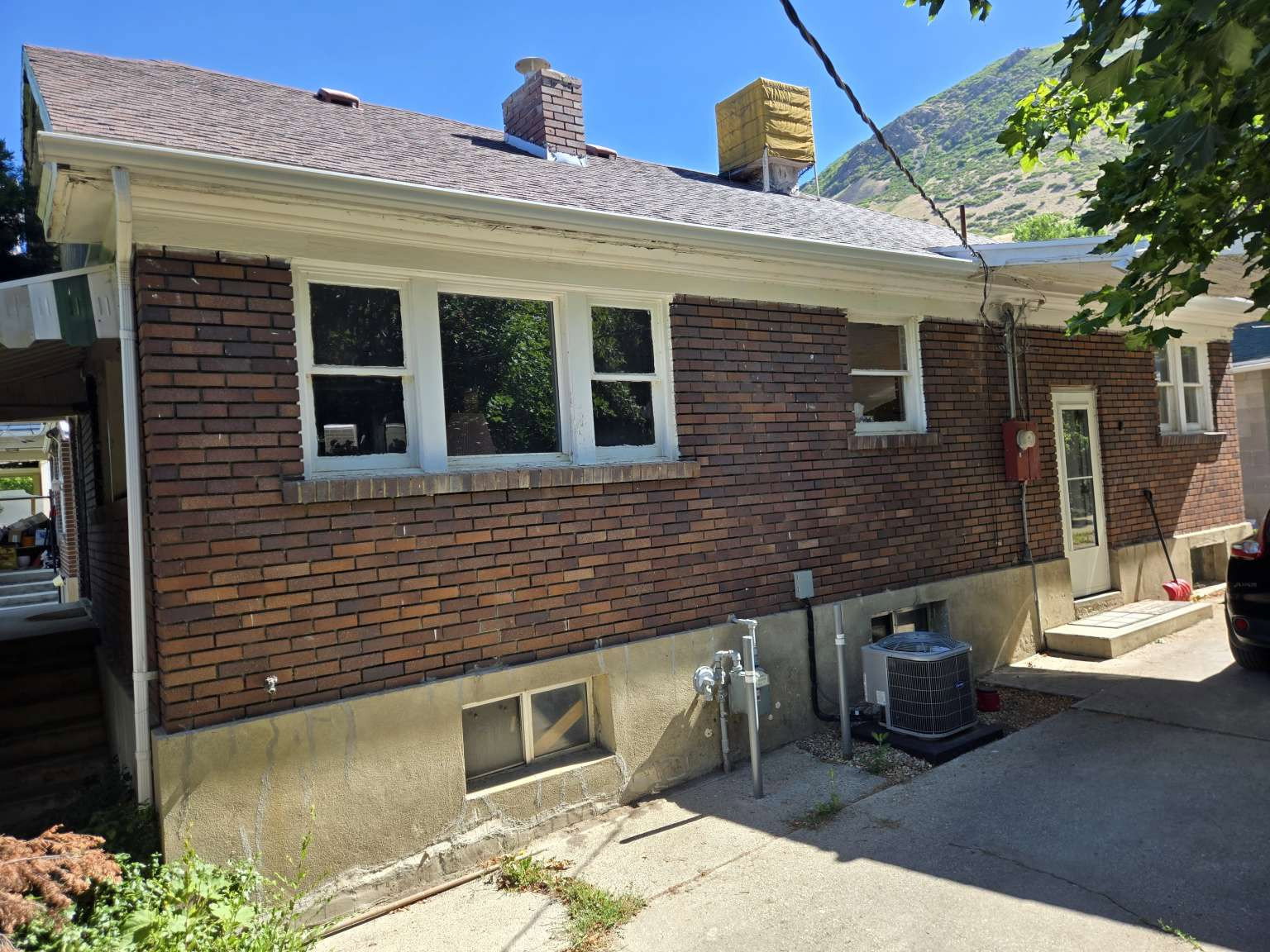 Brick exterior with white window trim and a brown shingle roof