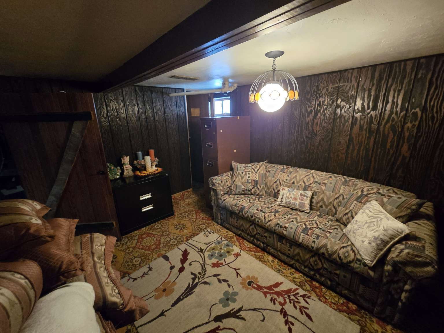 Recreational space featuring wood-paneled walls, exposed ceiling beams, and a ceiling-mounted light fixture