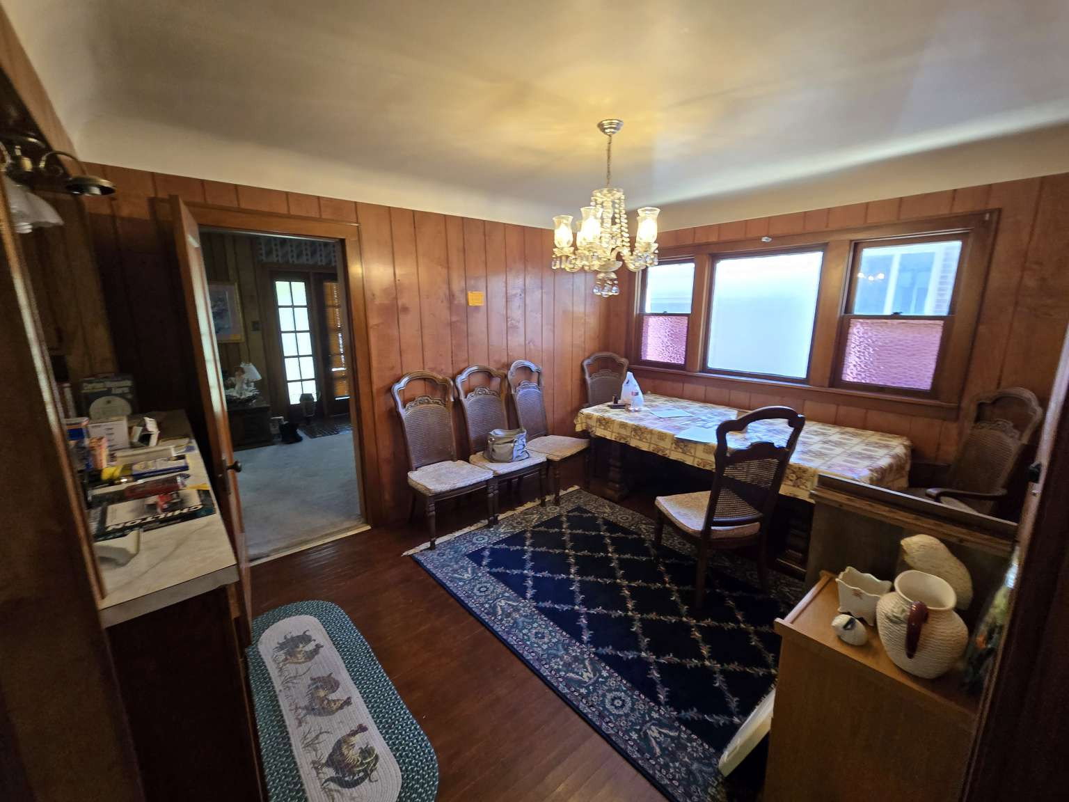 Dining area featuring wood-finish wall paneling, wood-finish flooring, a built-in window bench, and an ornate ceiling chandelier