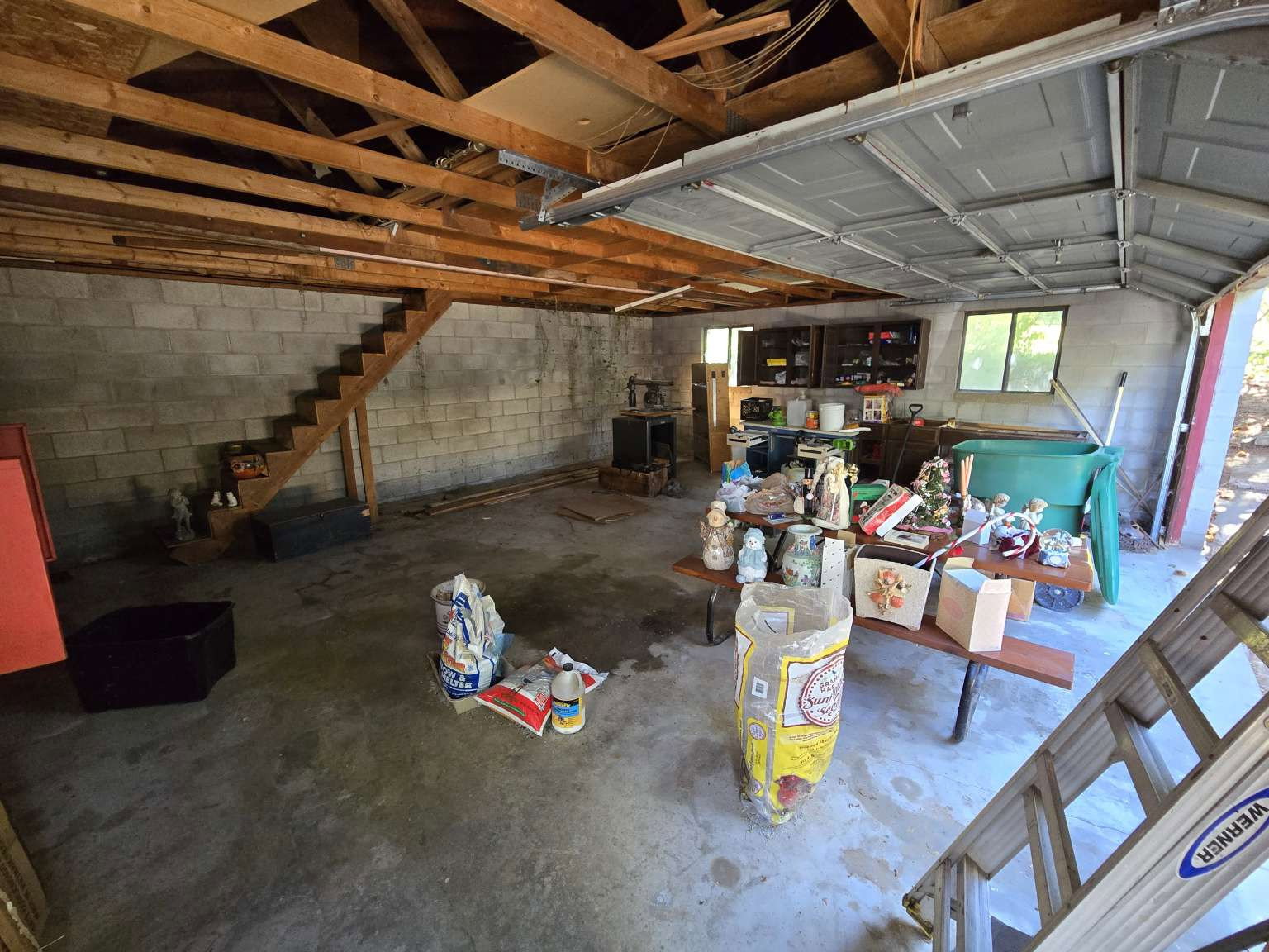 Expansive garage space featuring exposed wood beam ceiling, concrete block walls, and a finished concrete floor