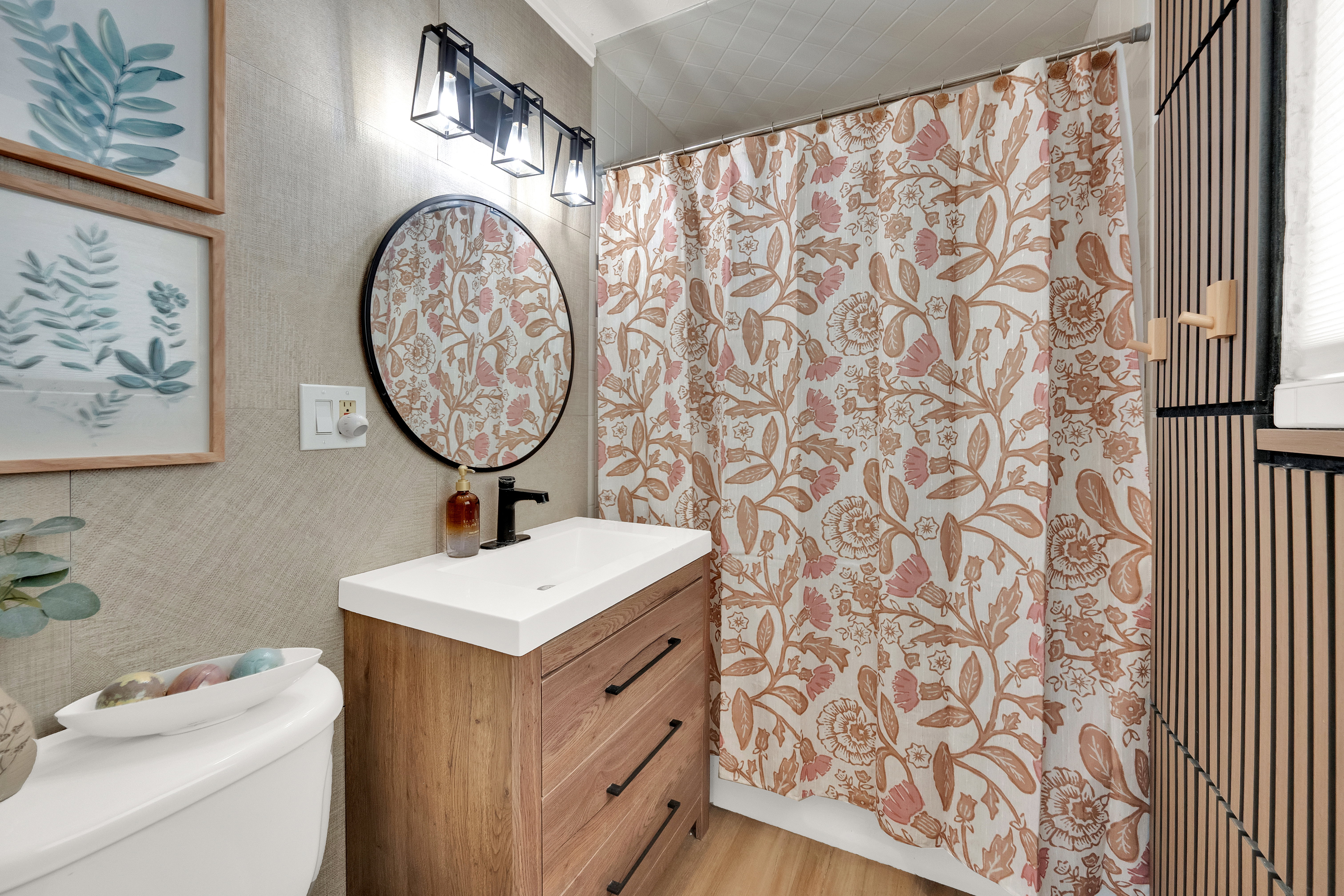 Bathroom featuring a wood-finish vanity with an integrated white sink and matte black faucet