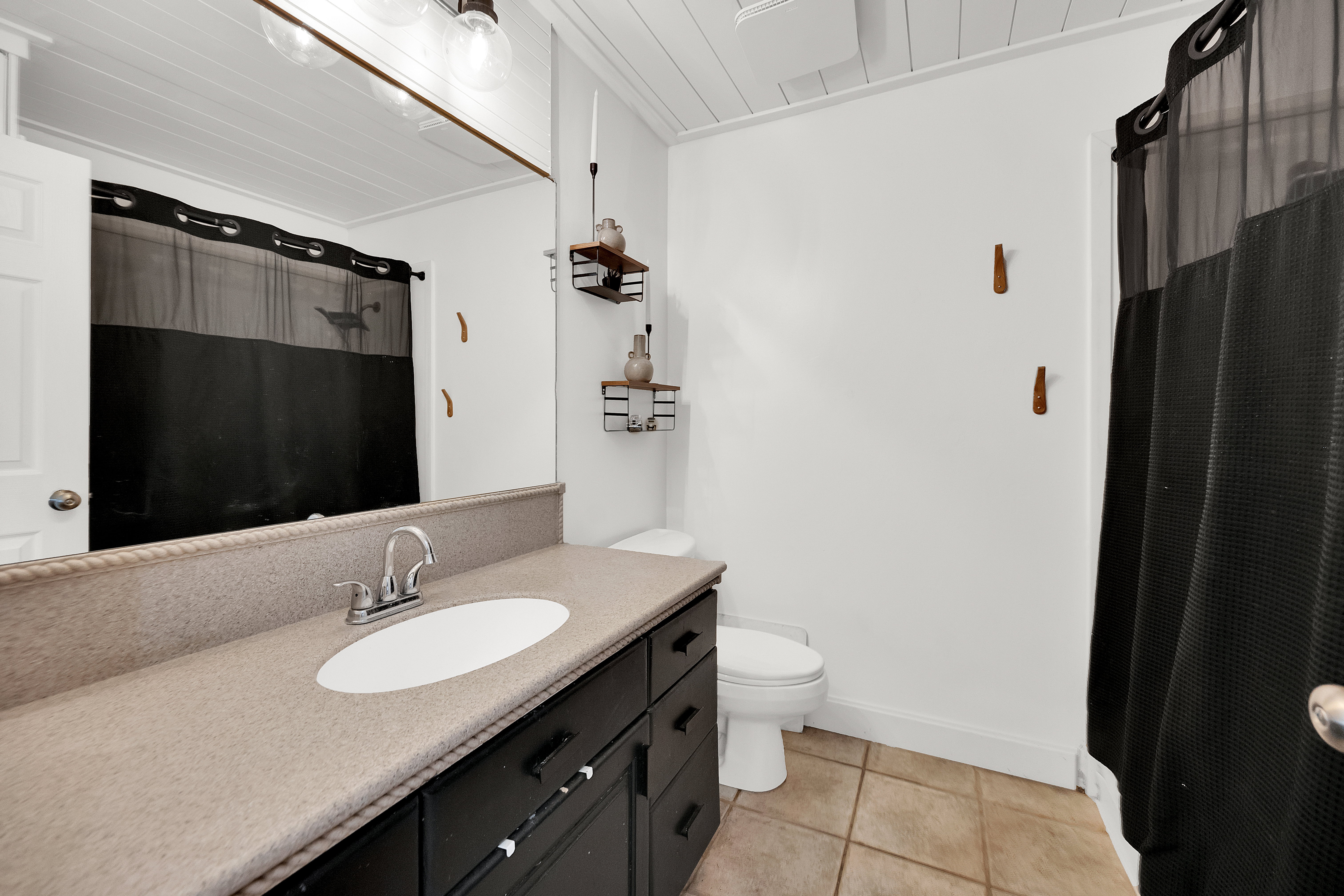 Bathroom featuring a black vanity with a light-toned countertop, a white oval sink, and a chrome faucet