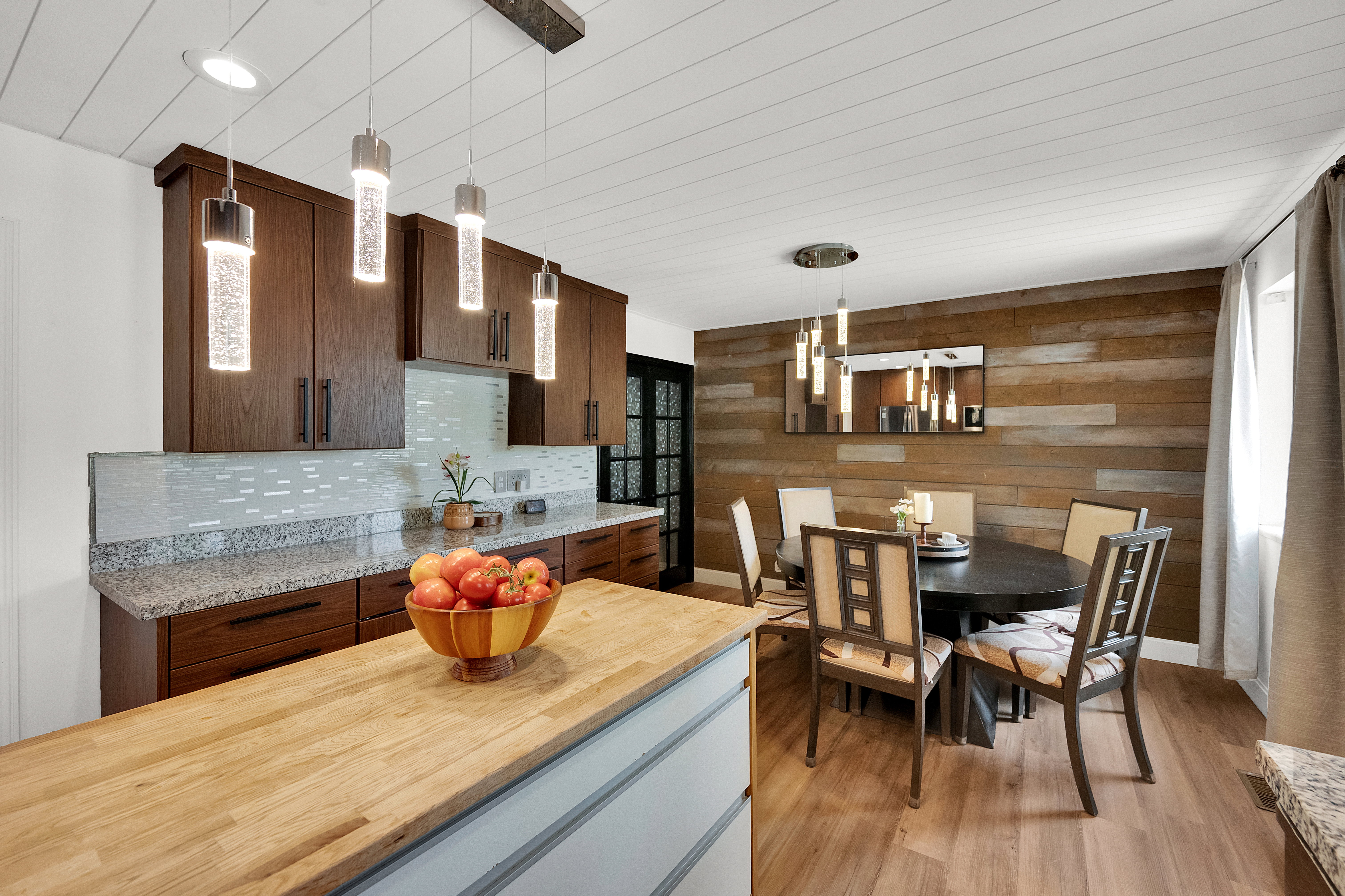 Kitchen and dining area featuring a wood-finish accent wall, wood-finish flooring, and a shiplap ceiling