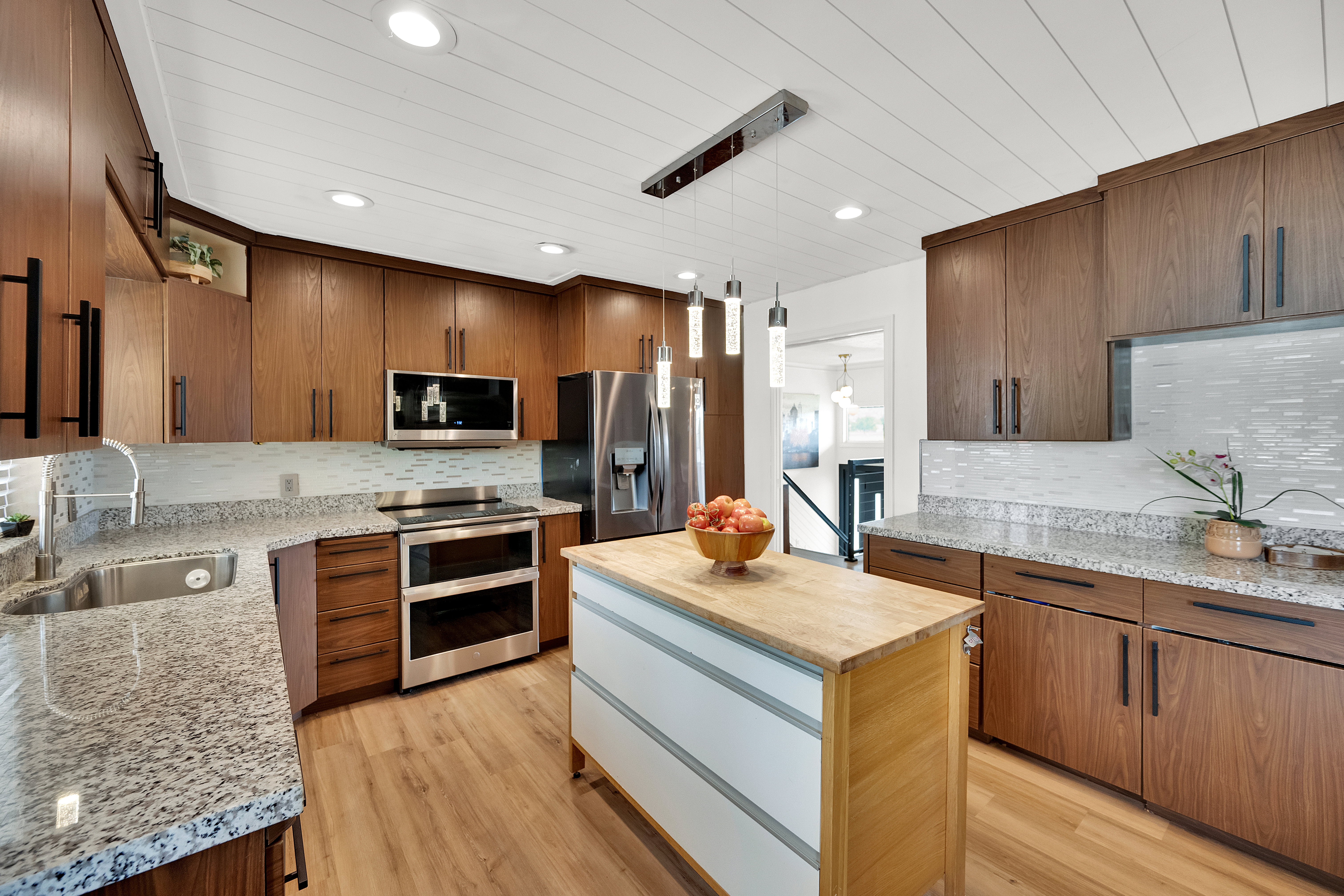 Kitchen featuring wood-finish cabinetry, granite countertops, and stainless steel appliances including a built-in double oven and refrigerator