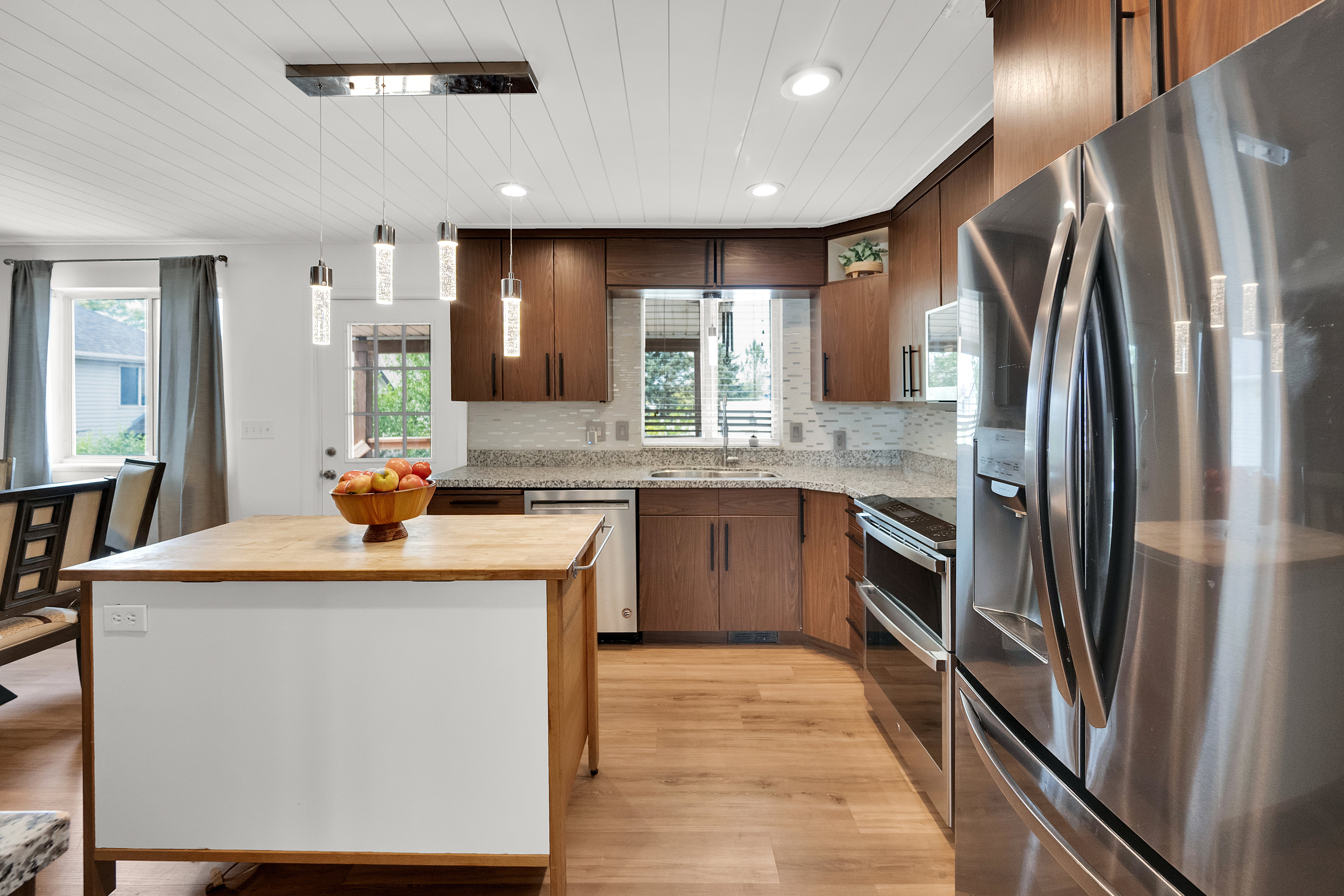 Kitchen featuring wood-finish flooring, shaker-style cabinetry, stainless steel appliances, and a central island with a wood countertop