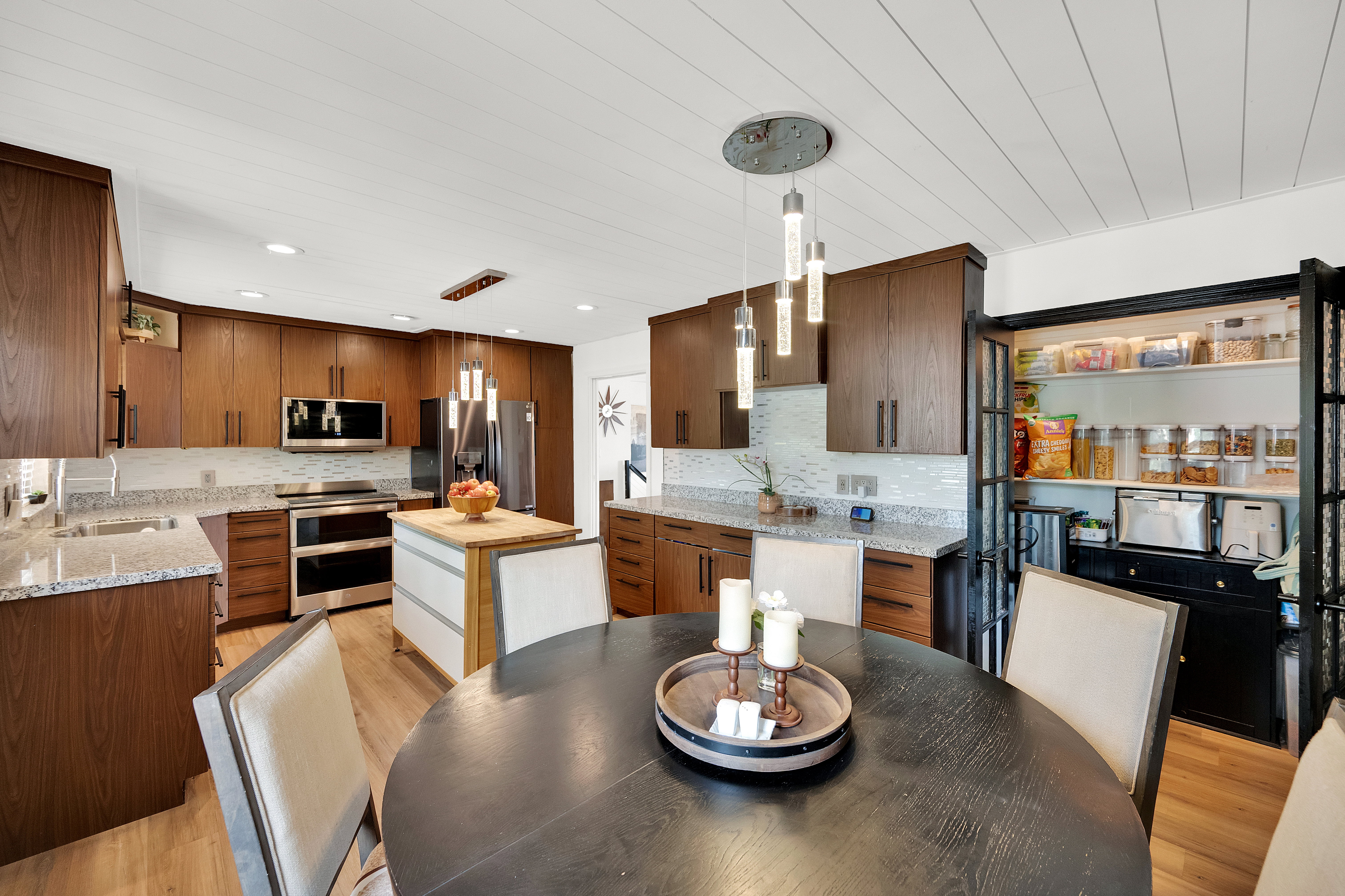 Modern kitchen featuring wood-finish cabinetry, stainless steel appliances, granite countertops, and a subway tile backsplash