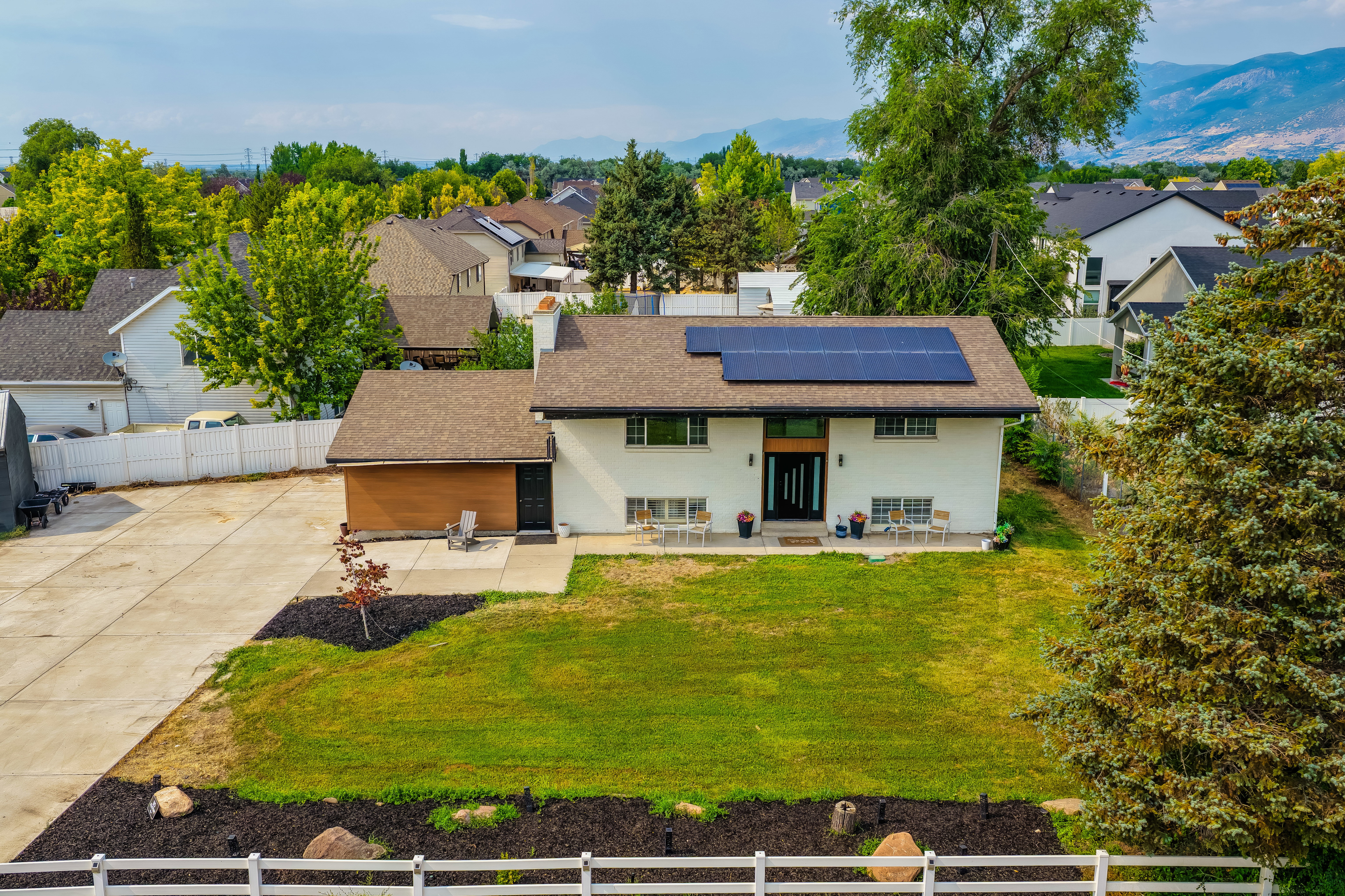 Split-level residence featuring a light-colored exterior and a brown shingle roof