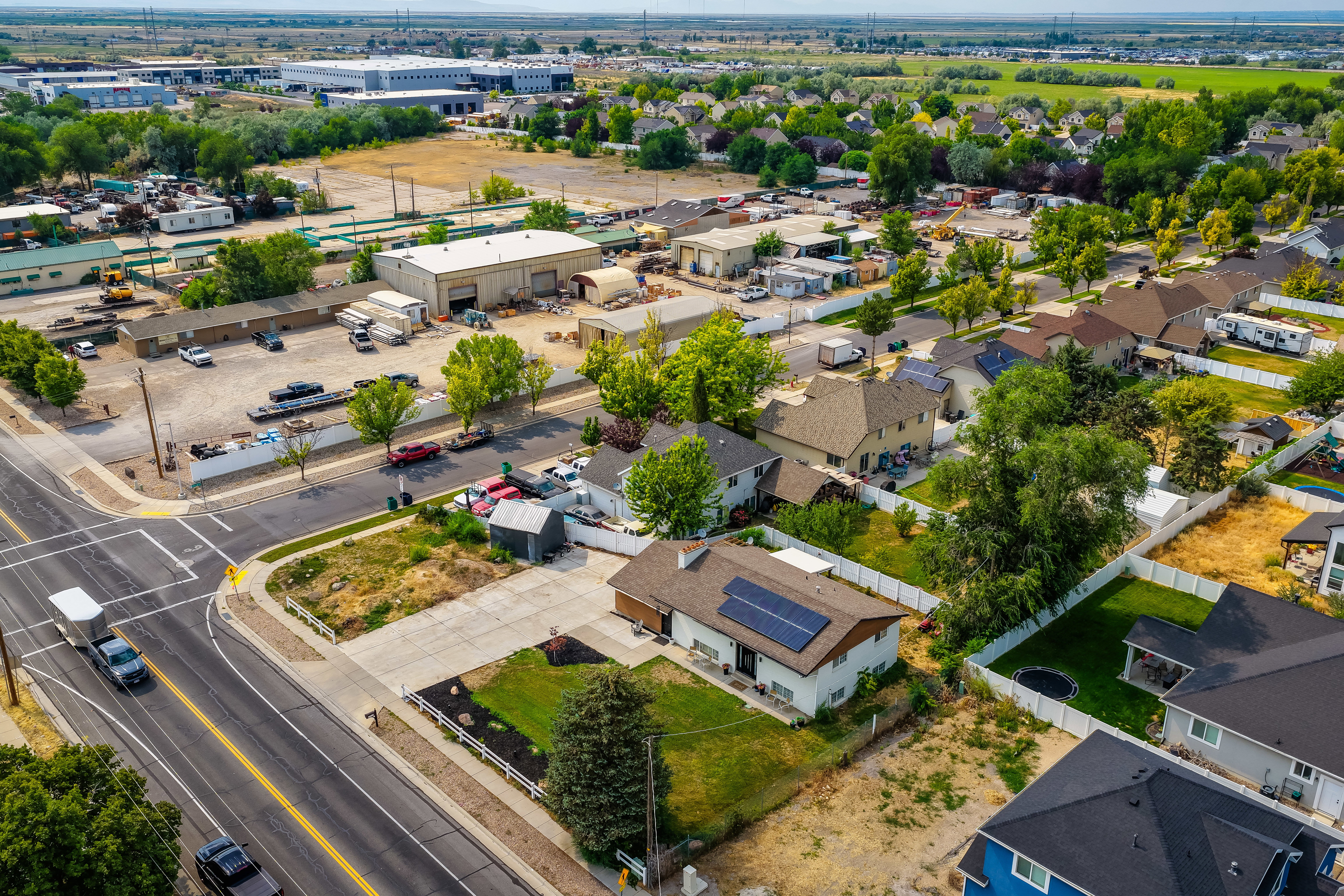 Aerial perspective highlighting a residential property with solar panels on the roof, a well-maintained front lawn, and mature trees