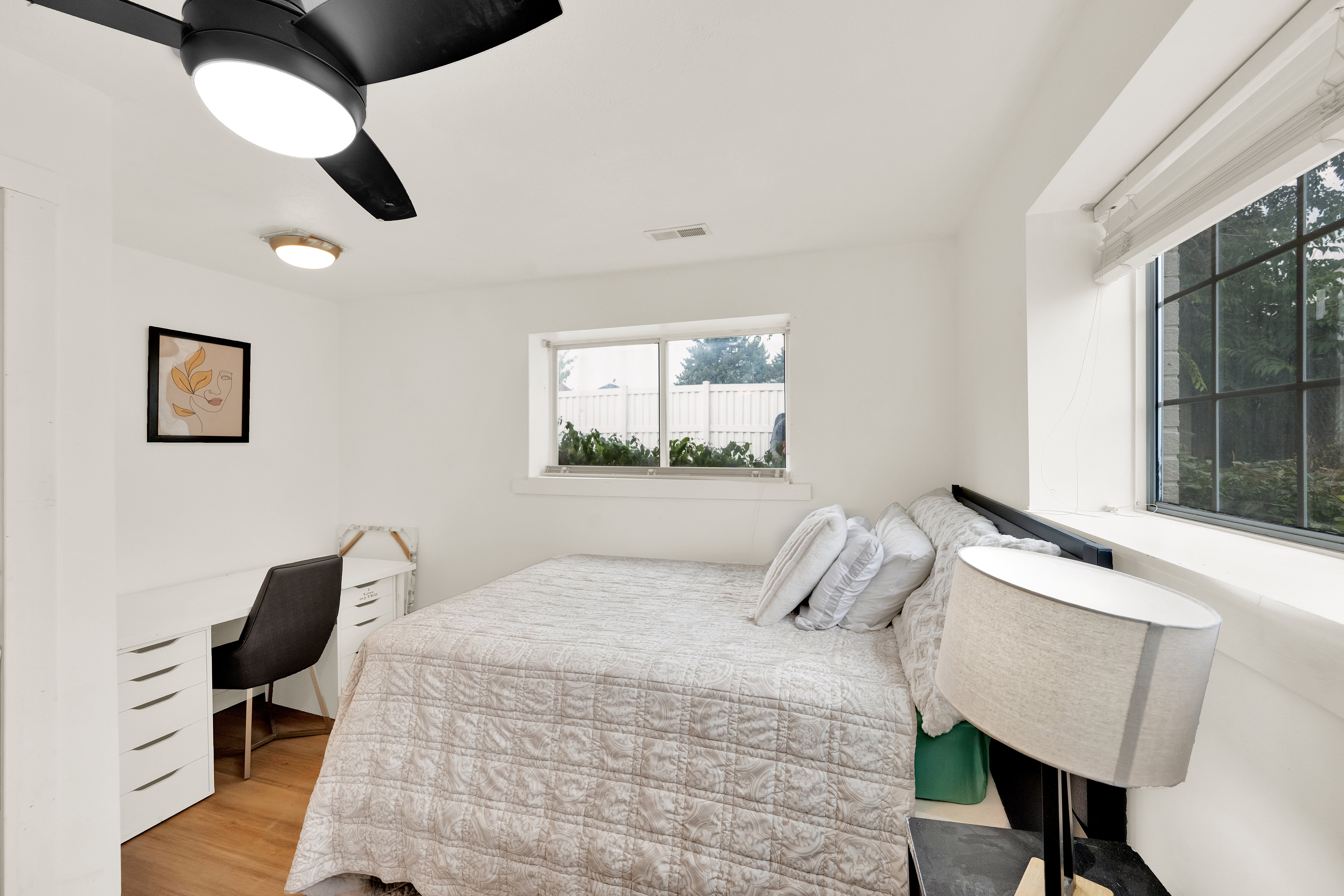 Bedroom featuring a ceiling fan with integrated lighting, wood-finish flooring, and white walls