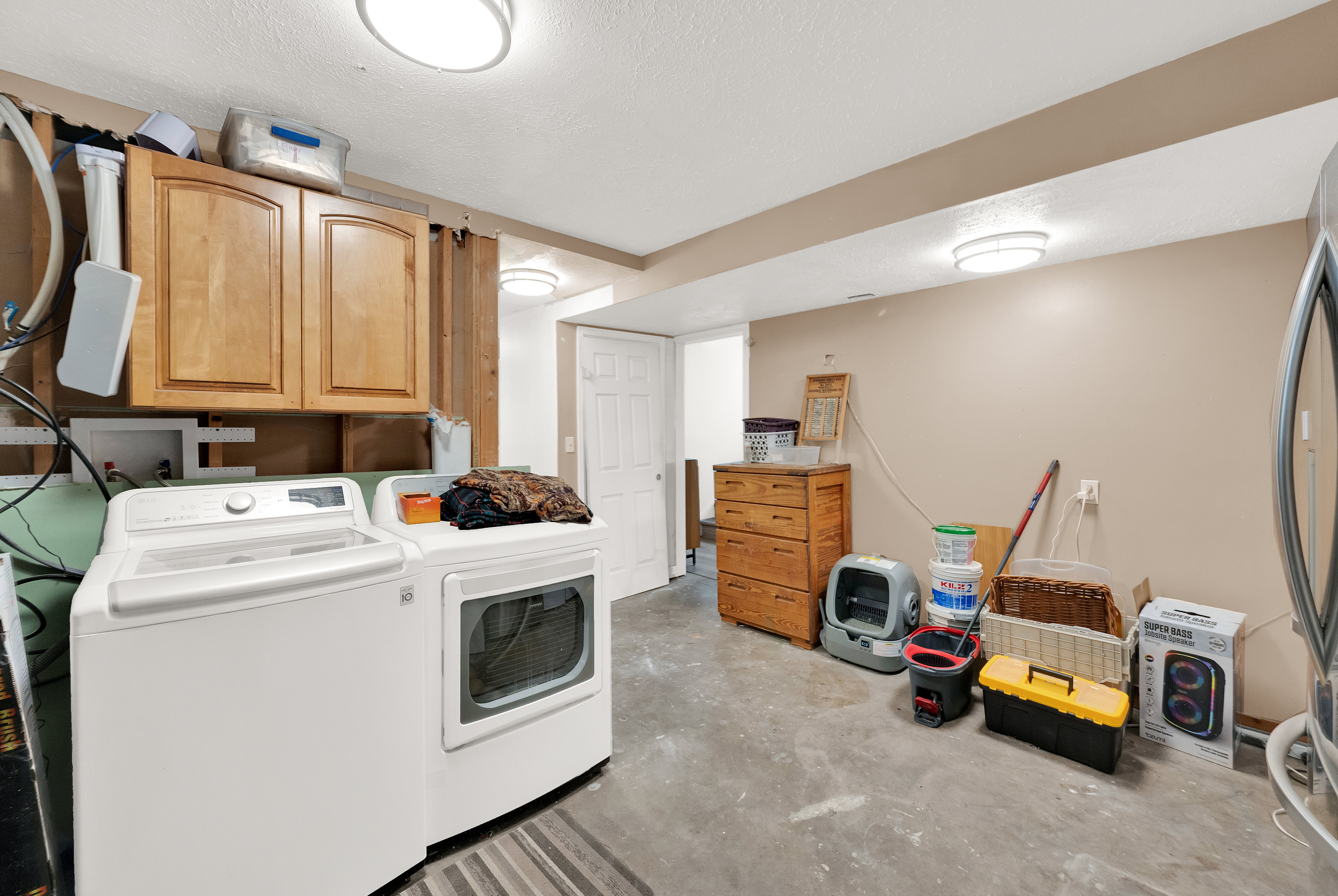 Utility area with concrete flooring, overhead lighting, and wall-mounted cabinetry
