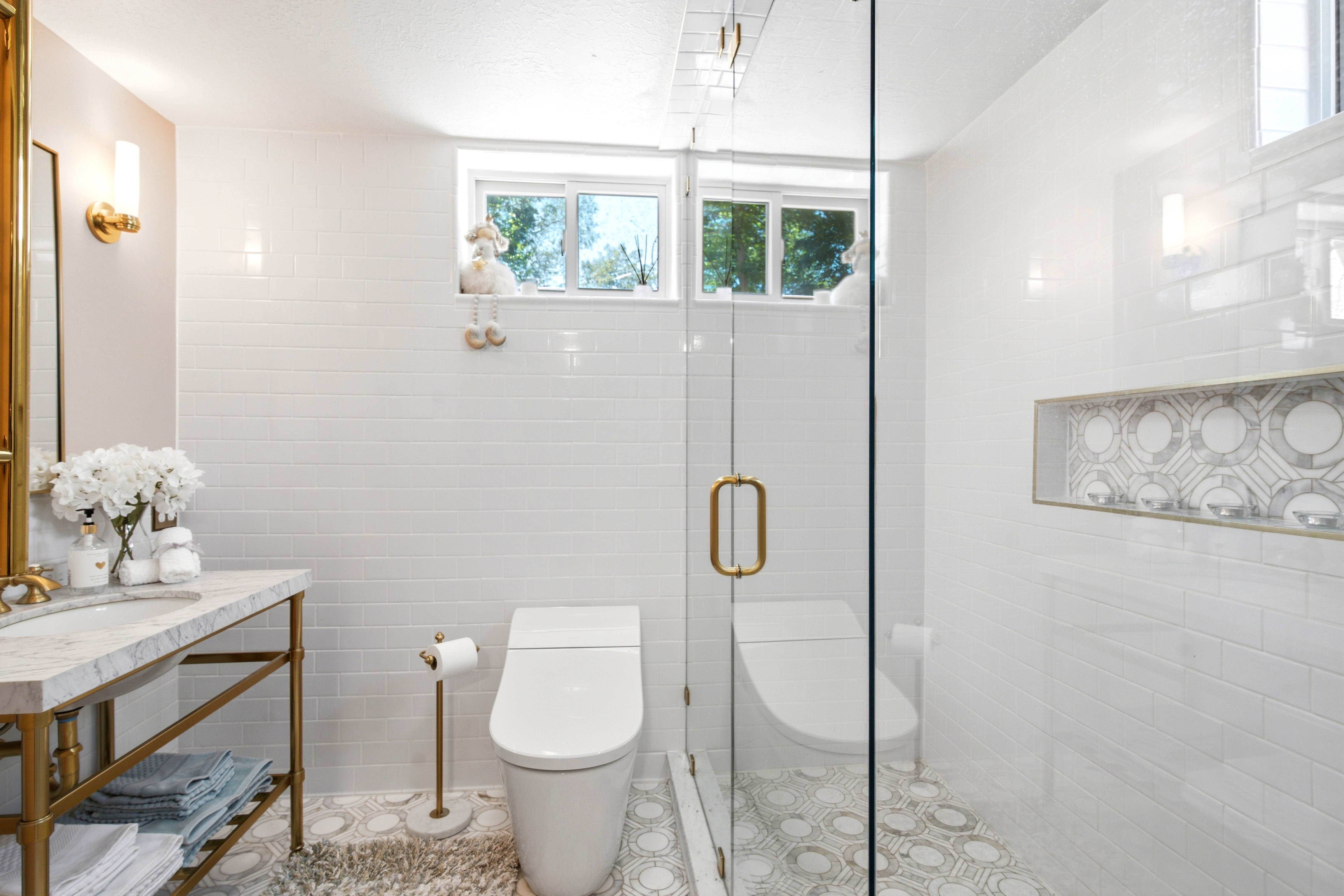 Euro glass-enclosed shower, white subway tile walls, and a patterned mosaic marble tile floor.