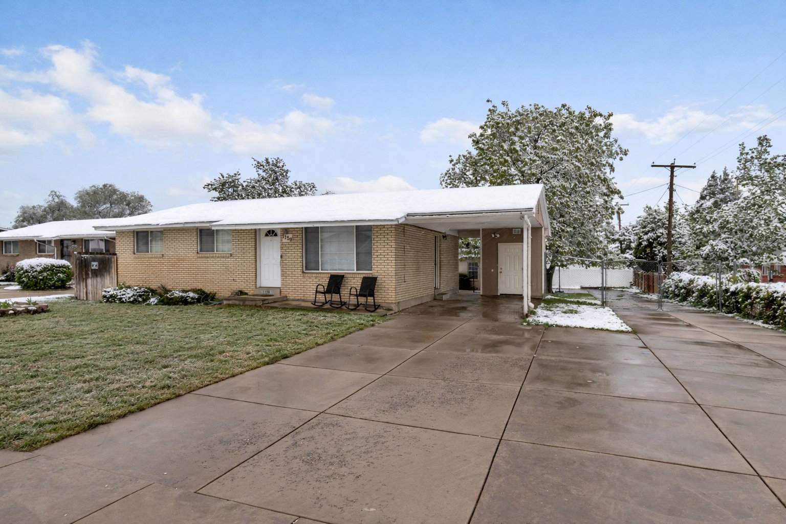 Brick exterior featuring a covered carport, concrete driveway, and front lawn